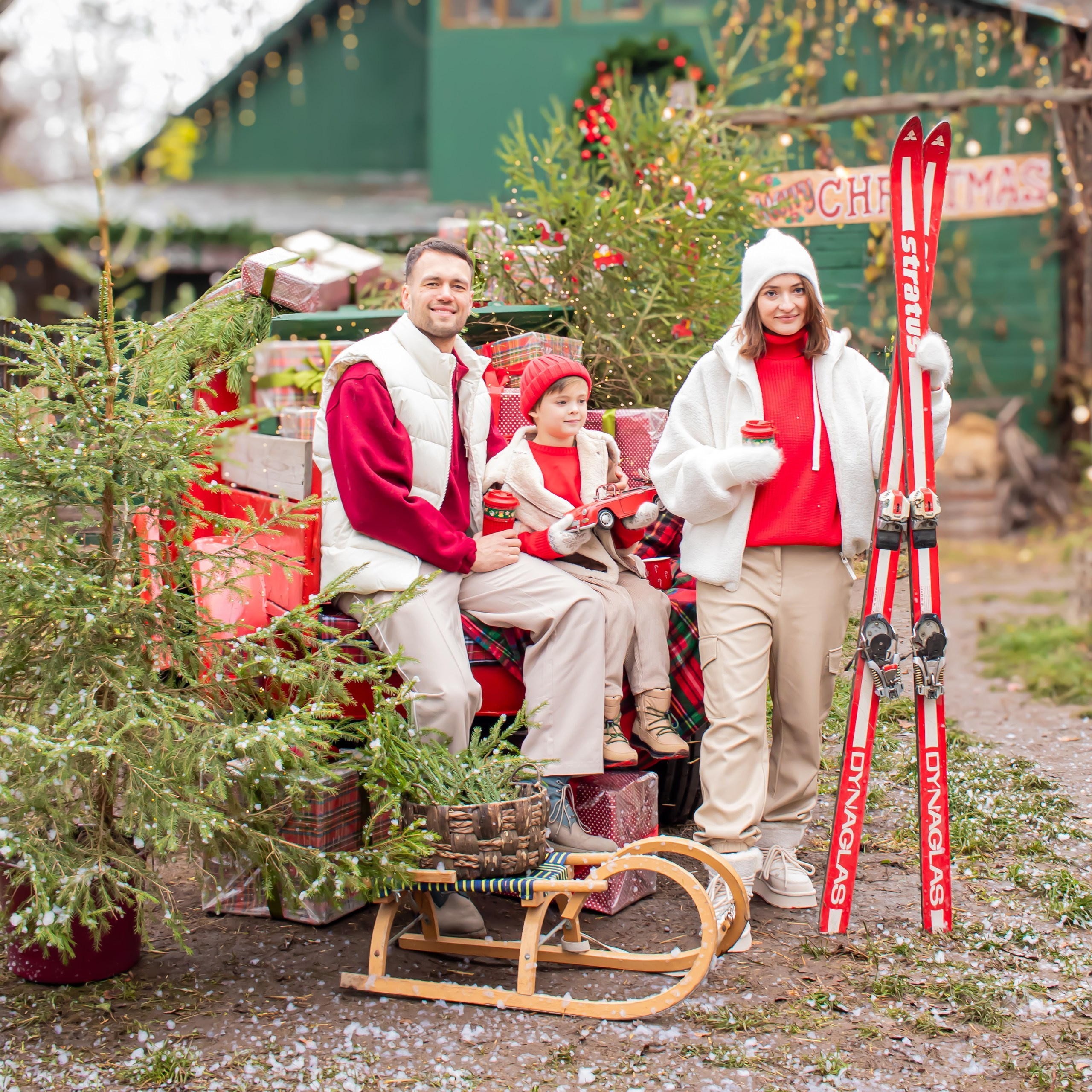 Семейная новогодняя фотосессия, мама папа и ребёнок с красными лыжами у рождественского шале, фотограф Карасёва Елена