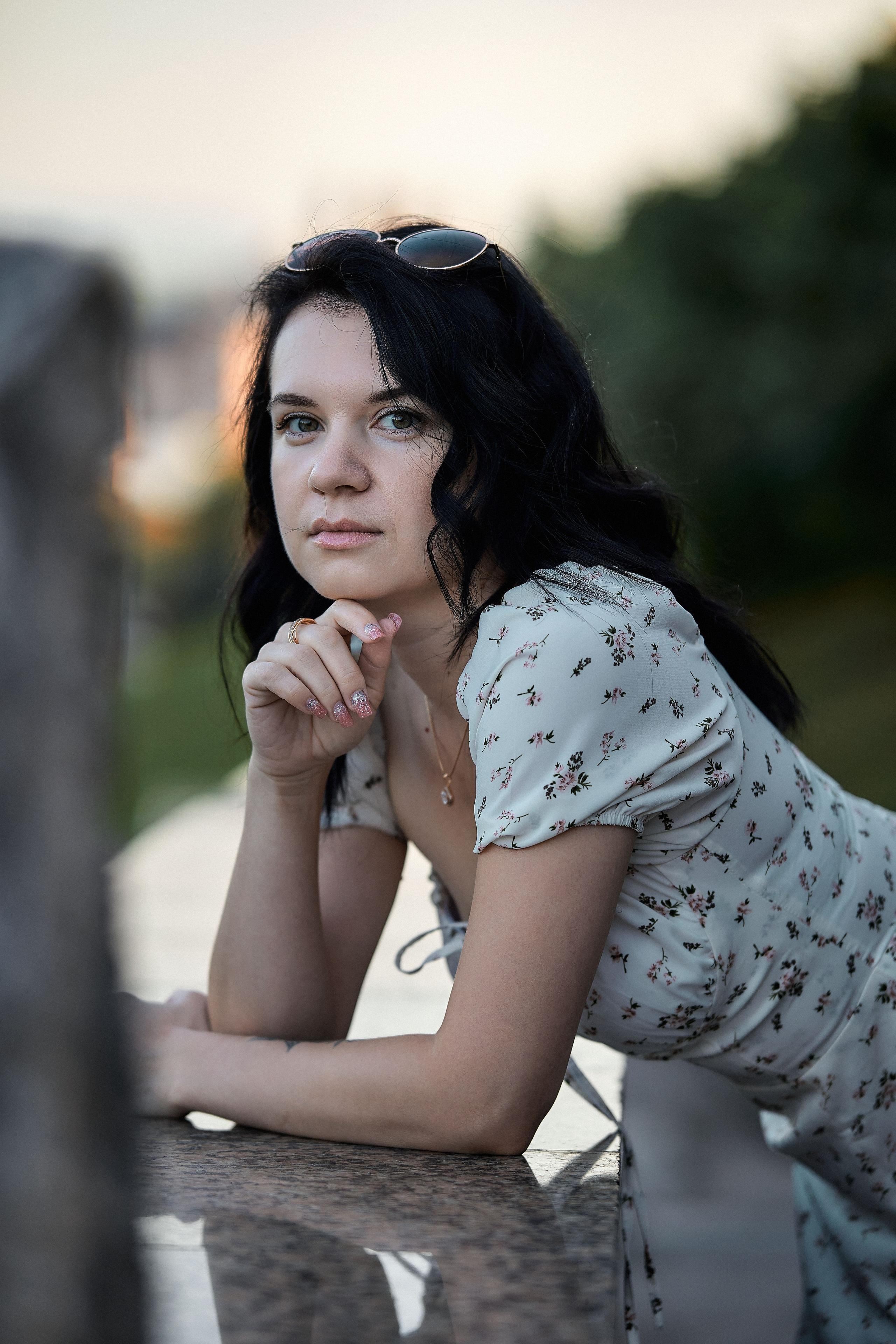 Молодая женщина в светлом наряде на фоне размытых городских силуэтов