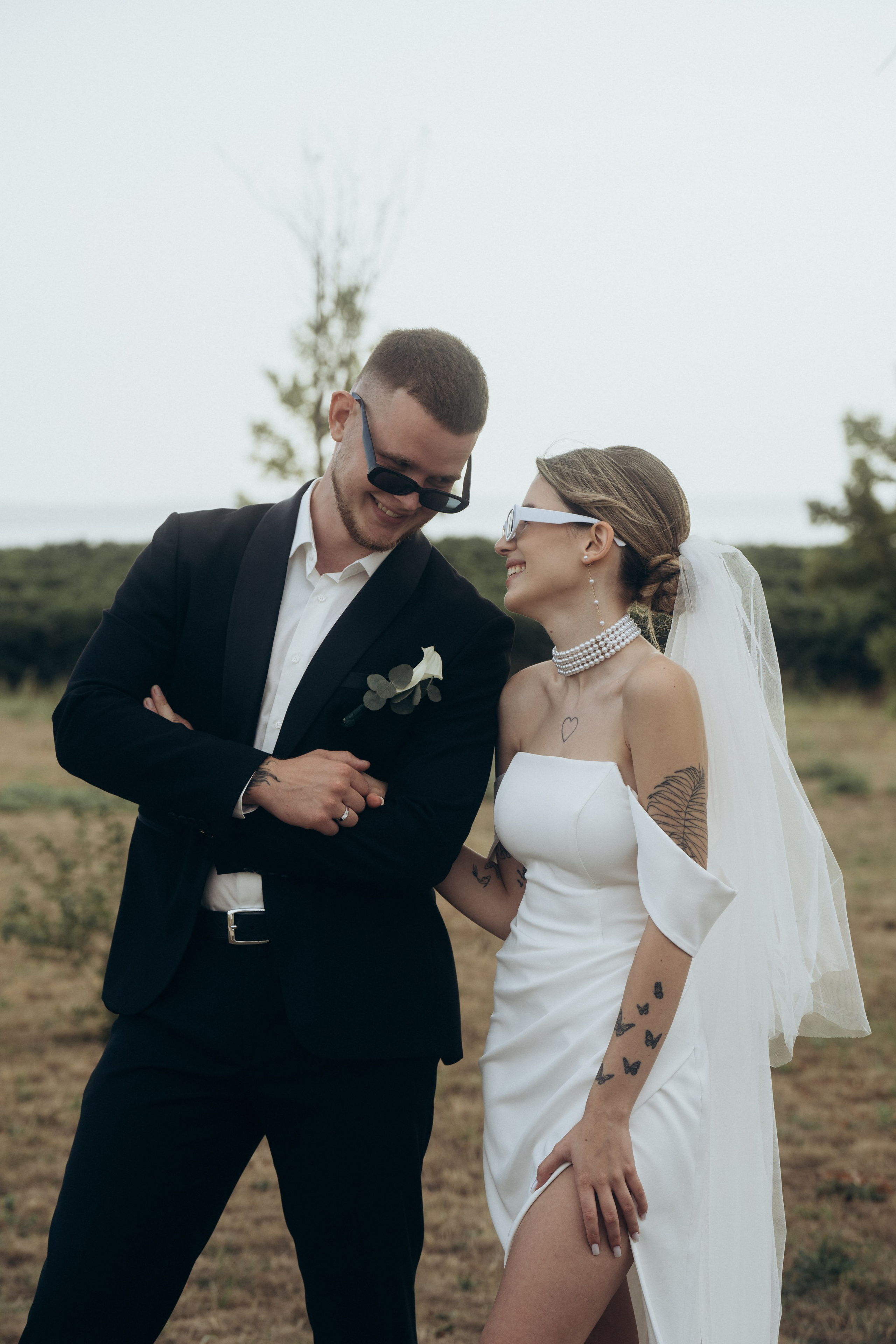 Фотография на которой молодожены в очках, смотрят друг на друга и улыбаются, свадебная фотография, сделанная в локациях Темрюка, поместье Голубицкое