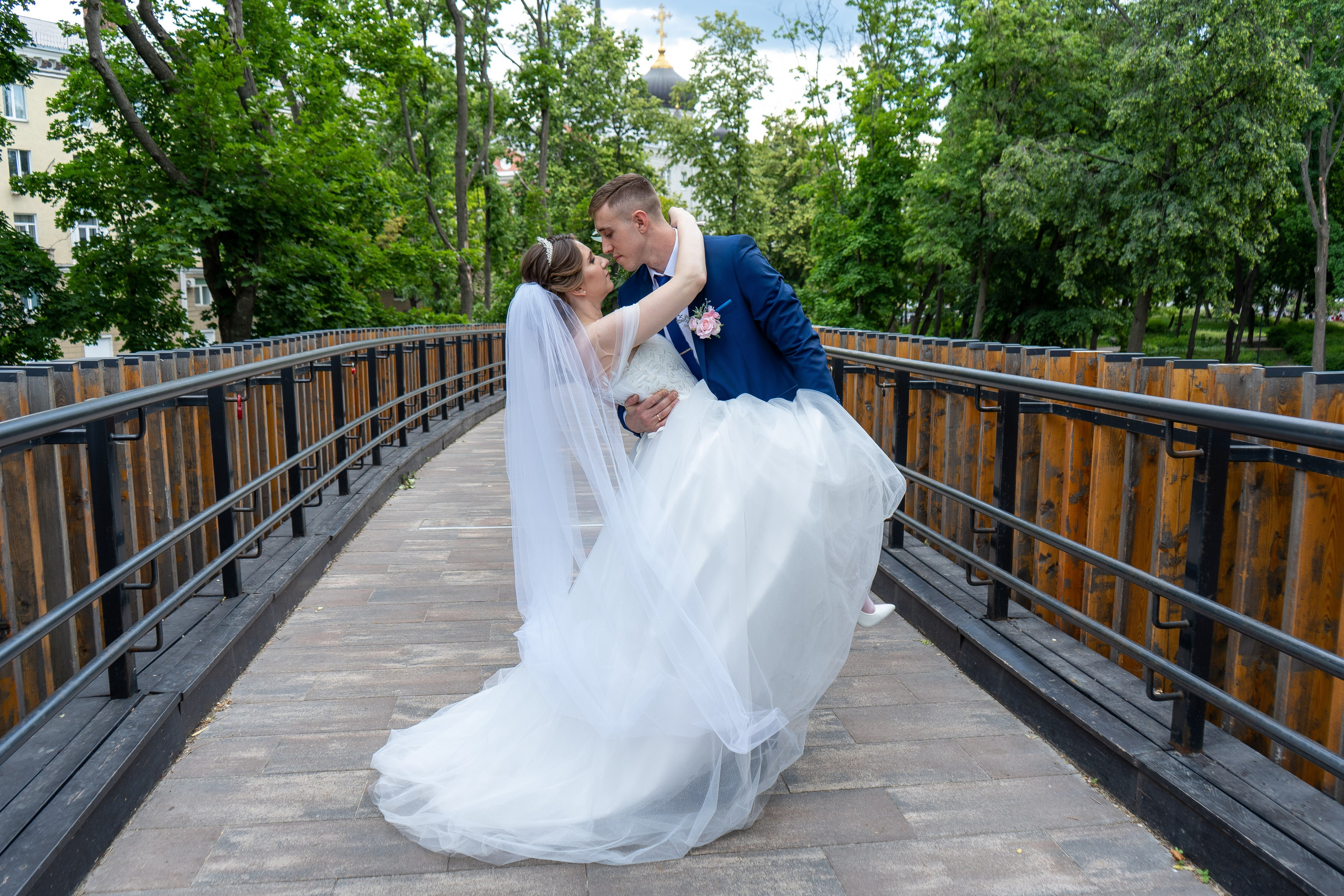 Жених кружит в танце невесту на деревянном мосту в парке Орленок в Воронеже