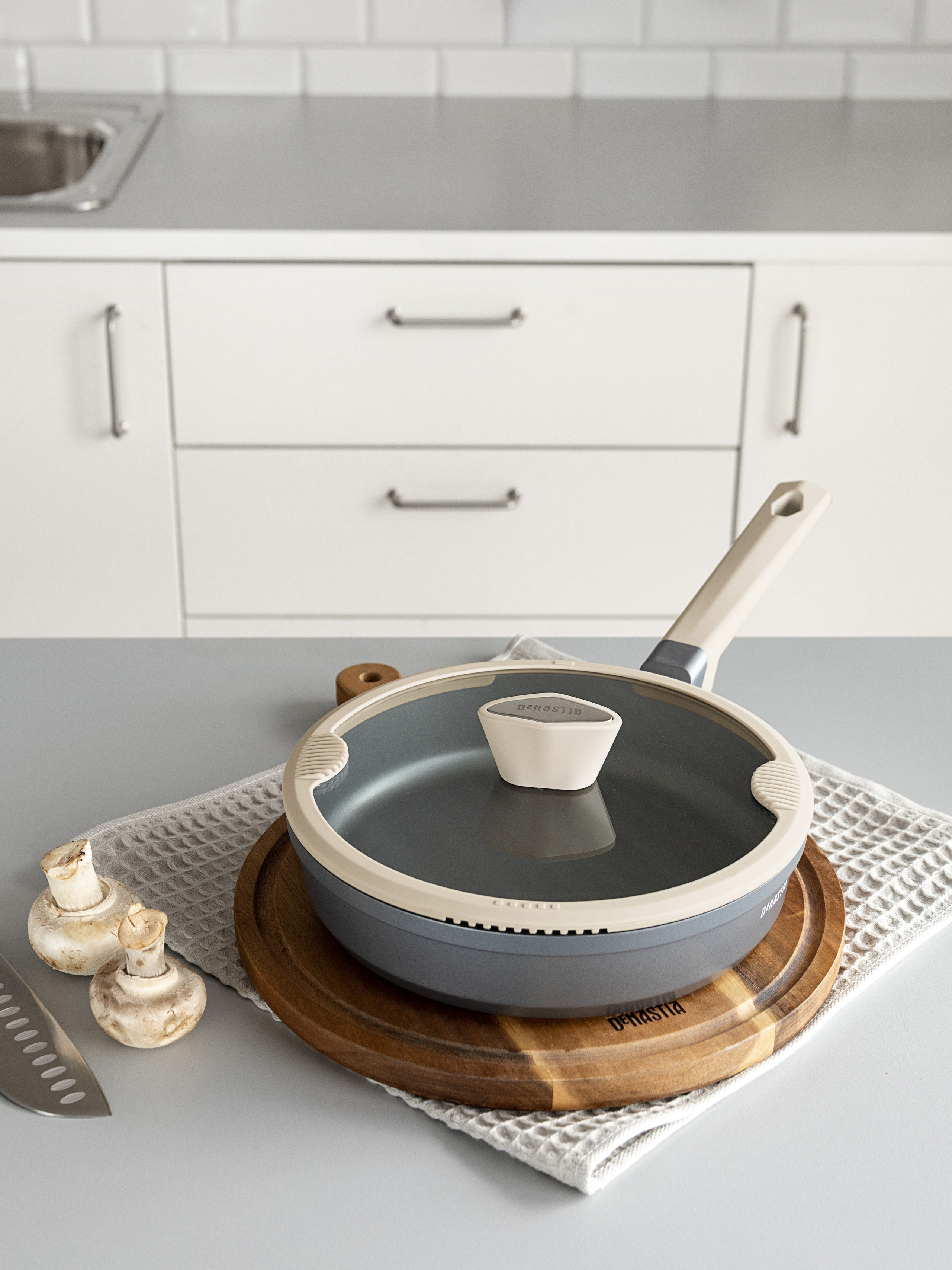 Сковорода с крышкой на столешнице среди других приборов | Фото для сайта производителя