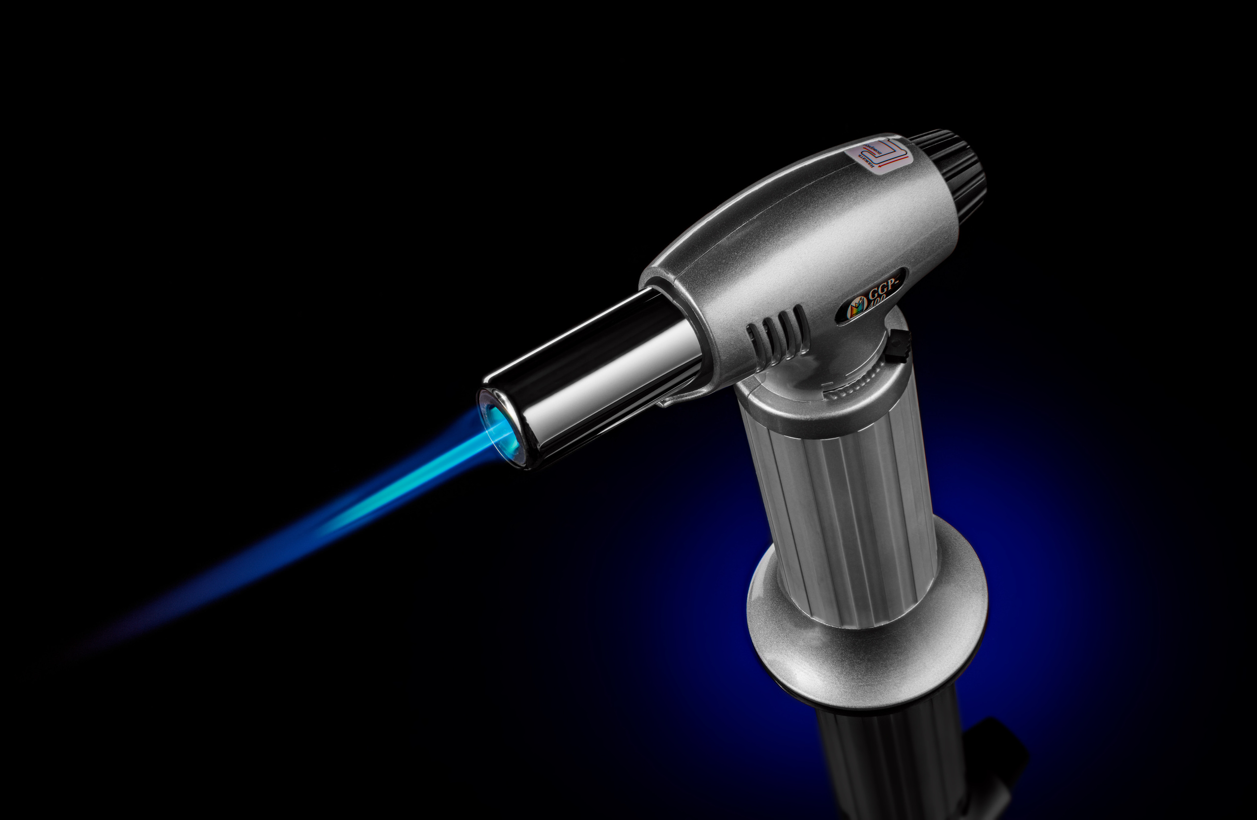  горящая  портативная газовая горелка на синем градиентном пятне на черном фоне