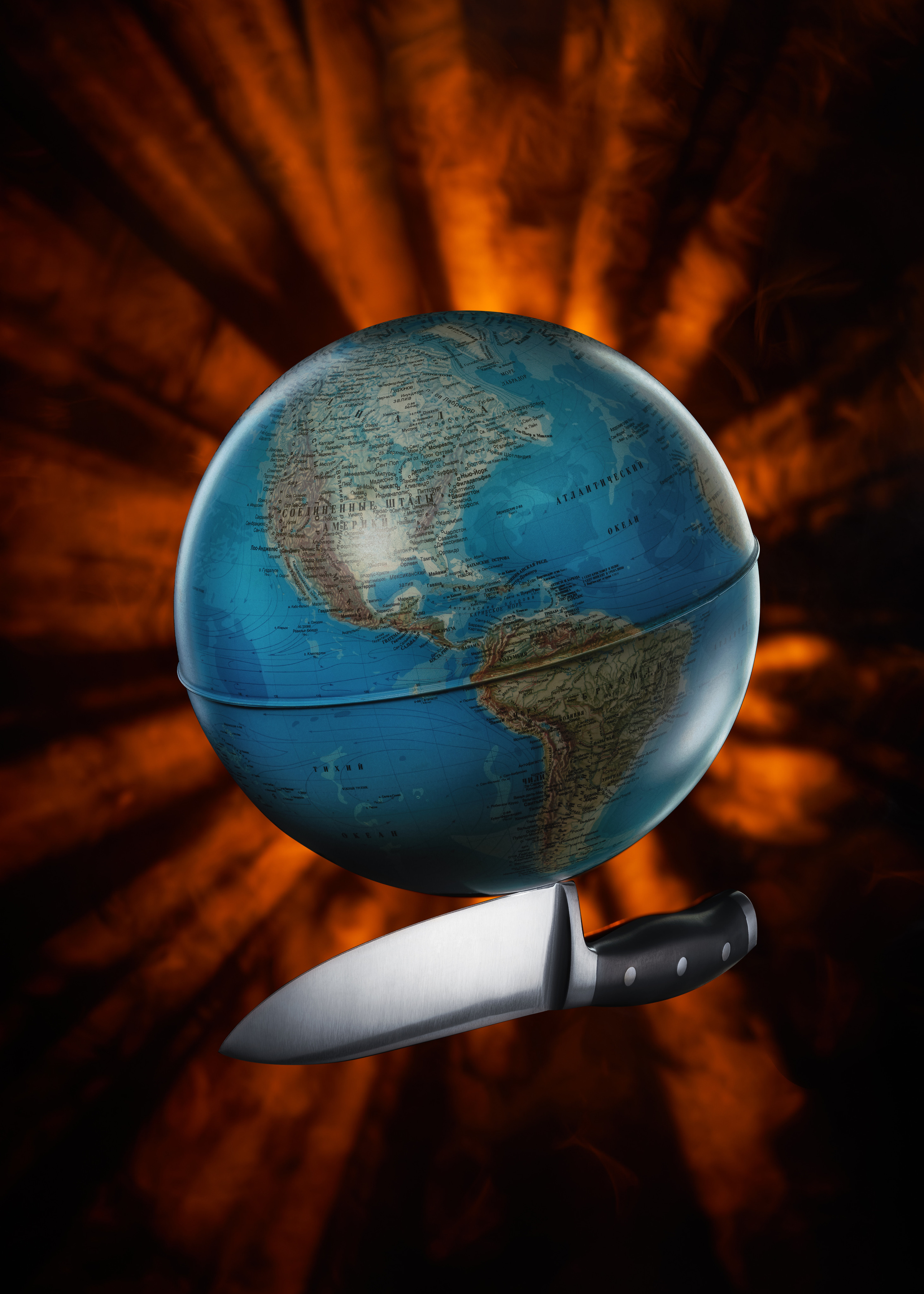 глобус  земного шара на лезвии ножа в лучах солнца идущих сквозь дым