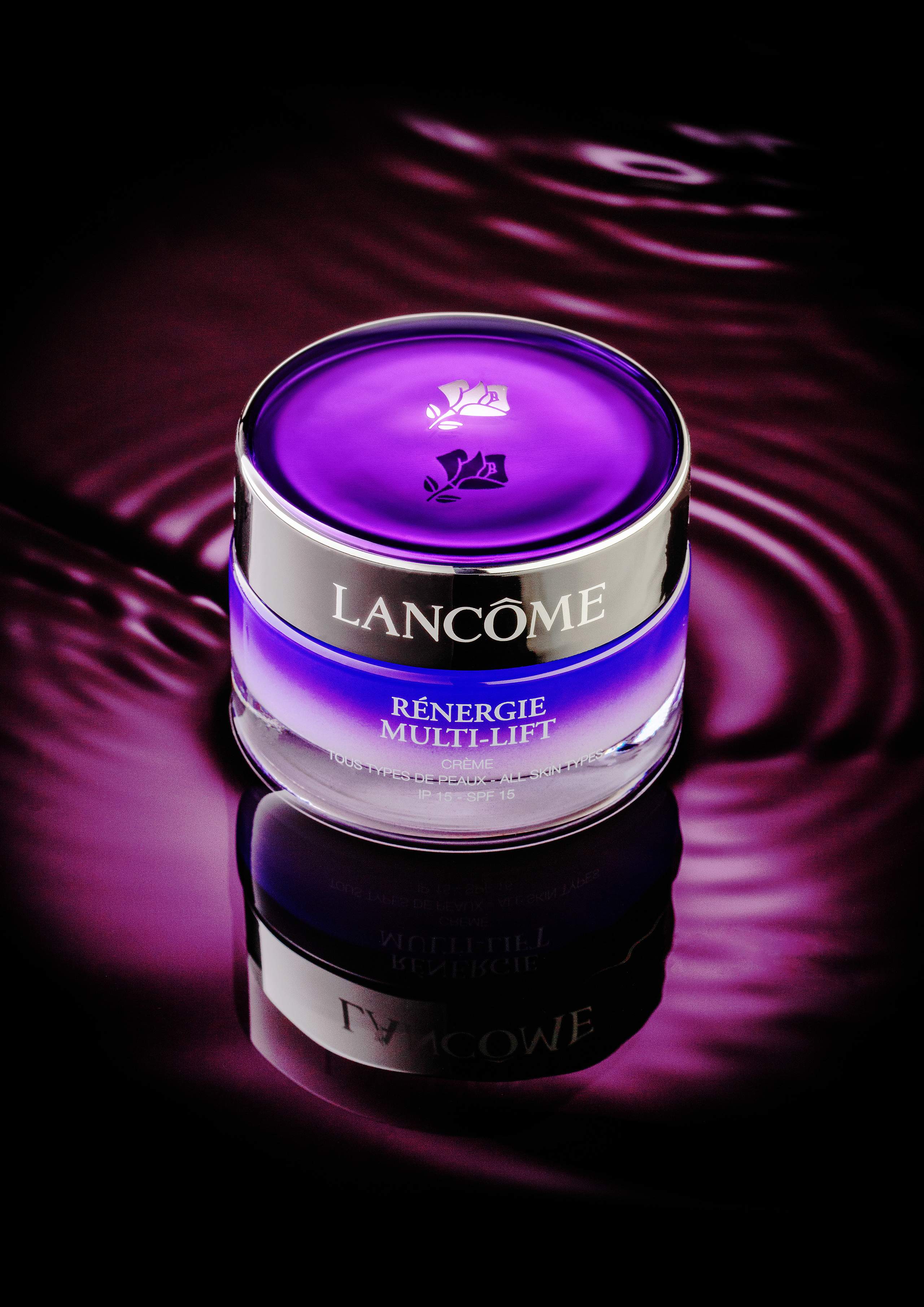 сиреневая  баночка с кремом Lancome плюхается в воду и расходятся волны сиреневого цвета 