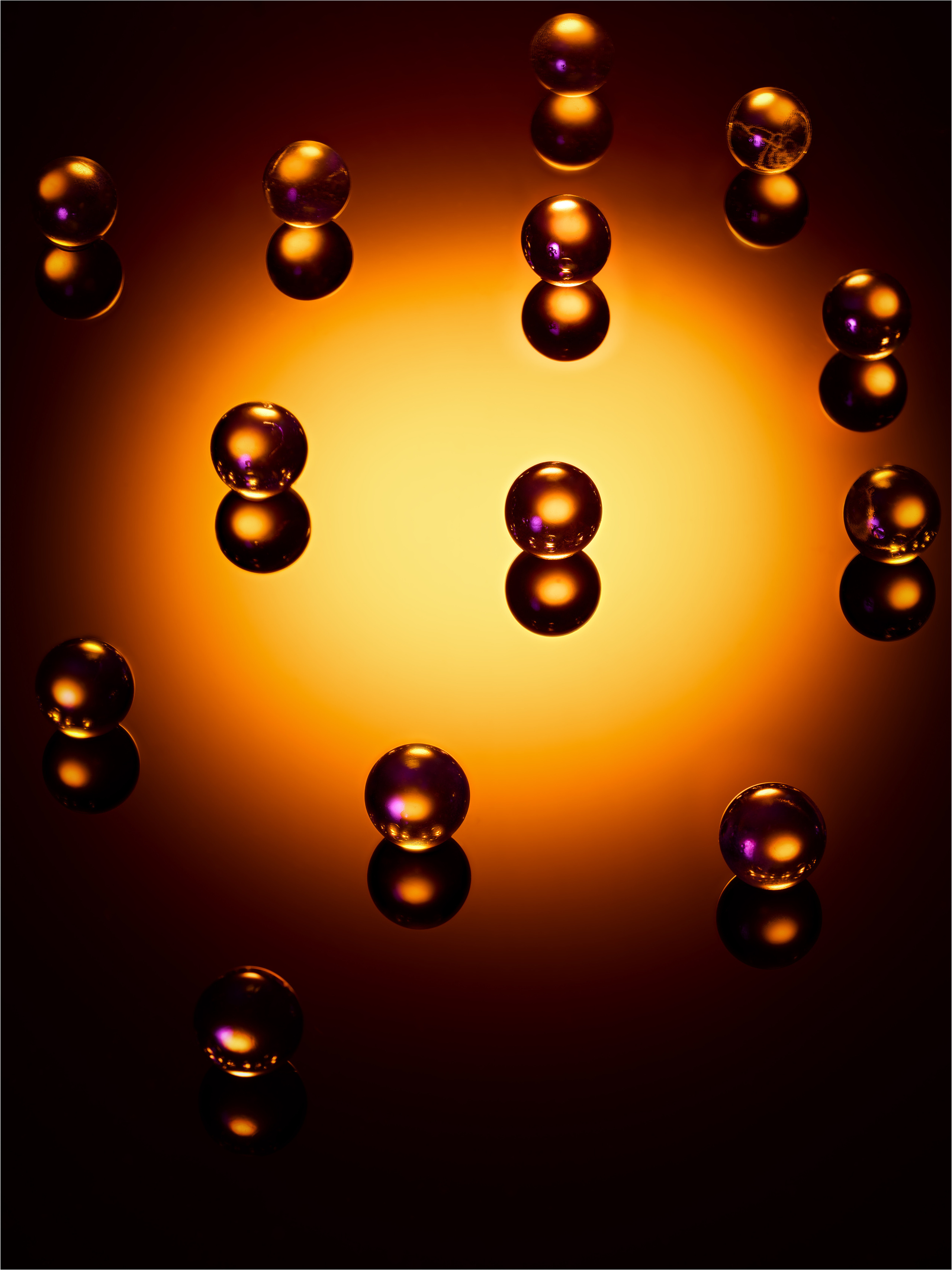 стеклянные шары на черном стекле освещены рыжим пятном по центру 