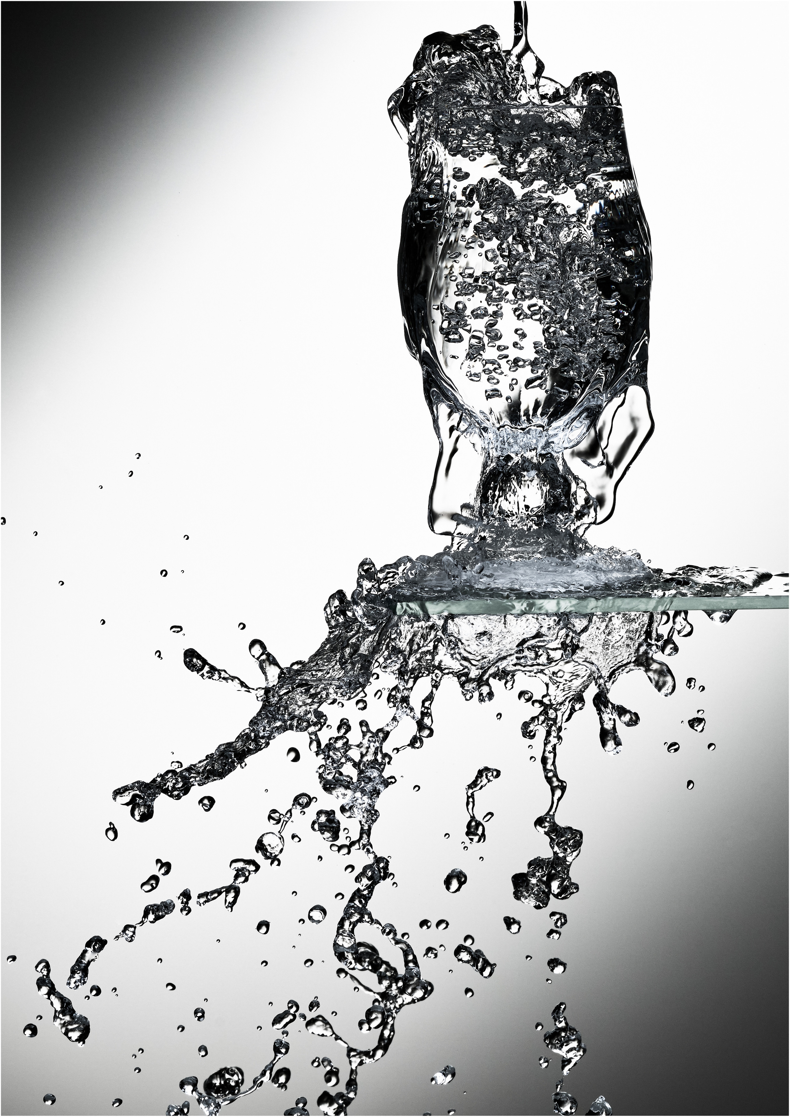 в винный бокал стоящий на стеклянной полке льётся вода через край и разбрызгивается-так заморожено