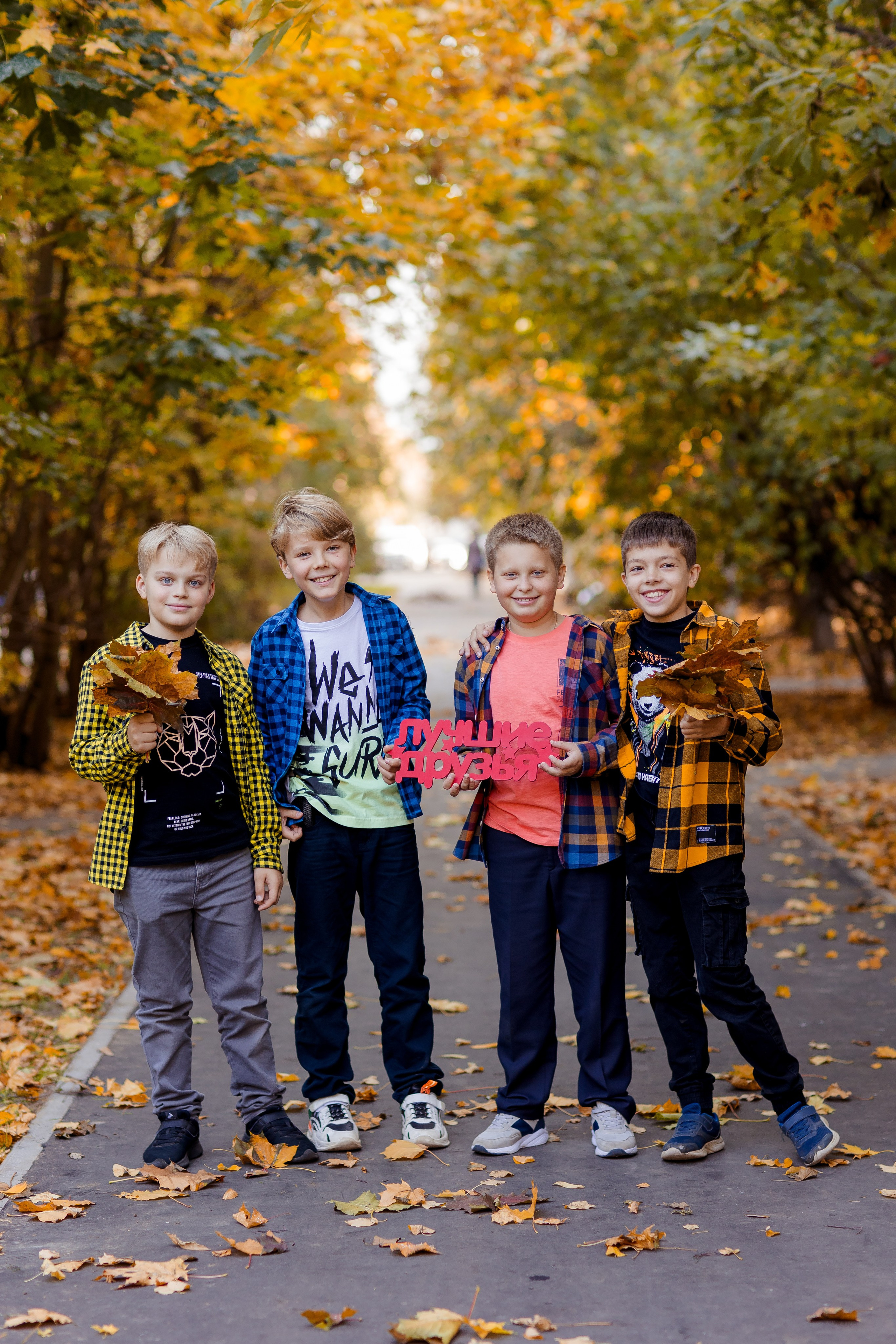 Мальчики друзья фотографируются с осенними листьями