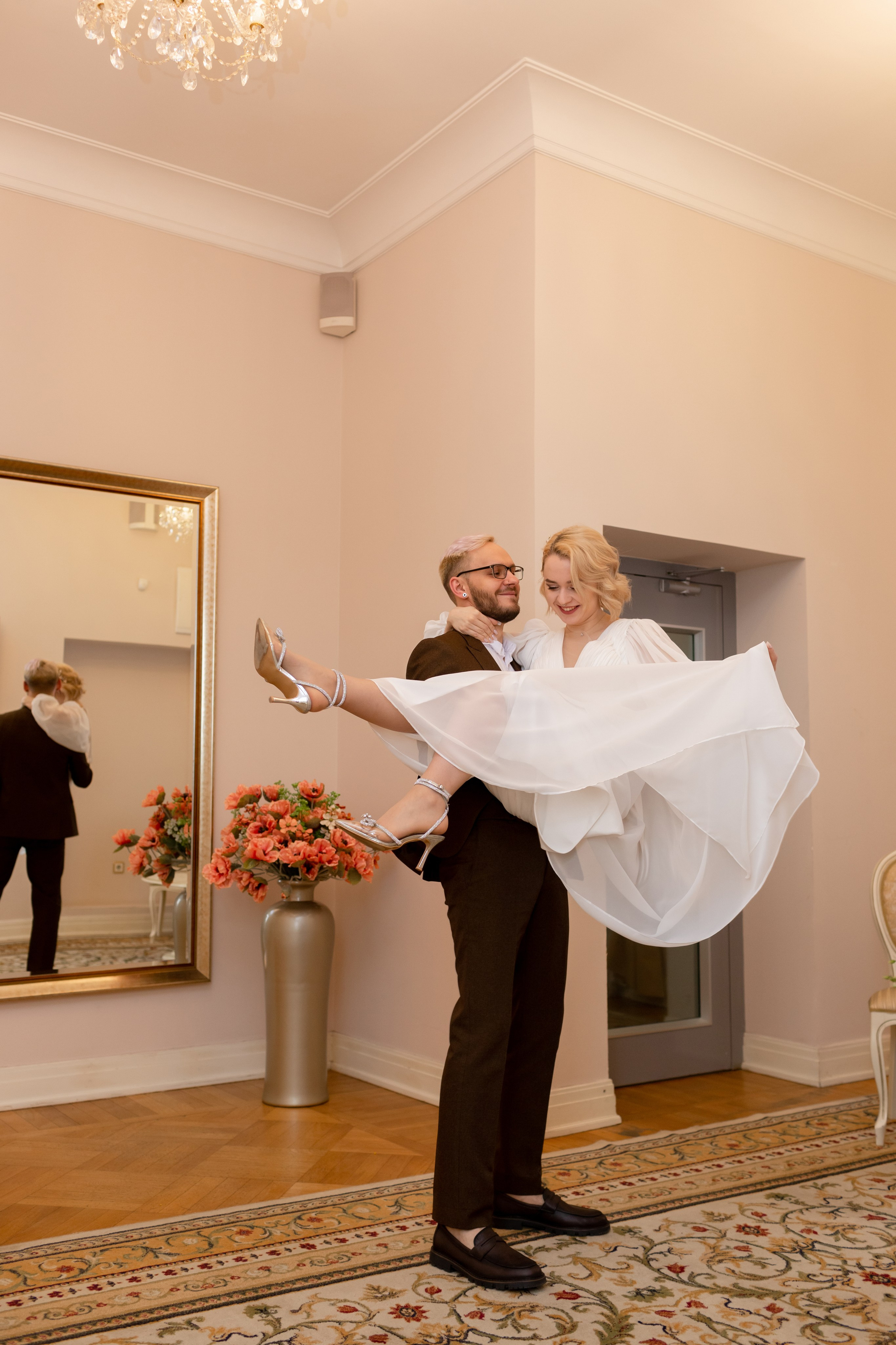 Жених весело кружит невесту на руках.