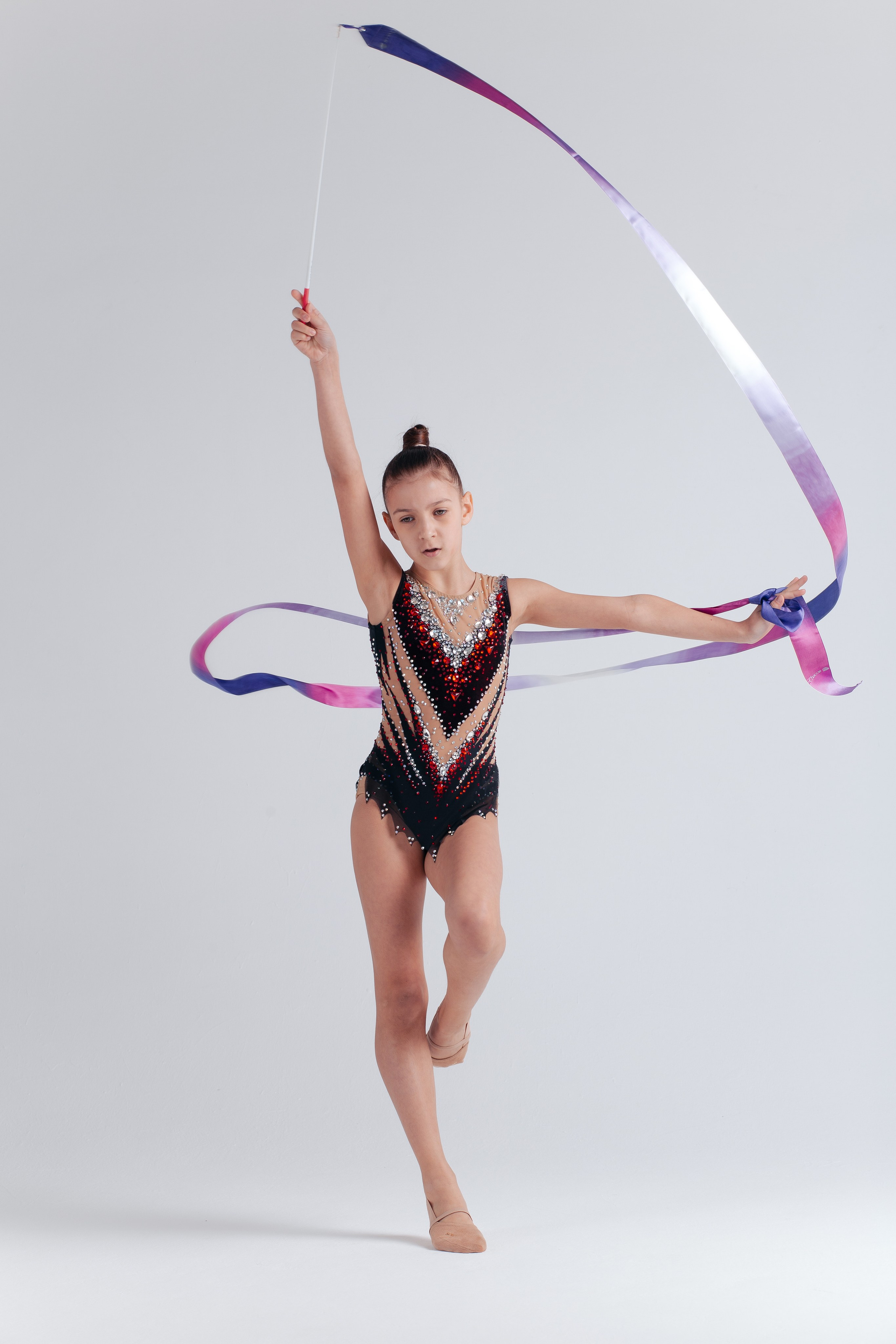 Девочка гимнастка занимается художественной гимнастикой с лентой.