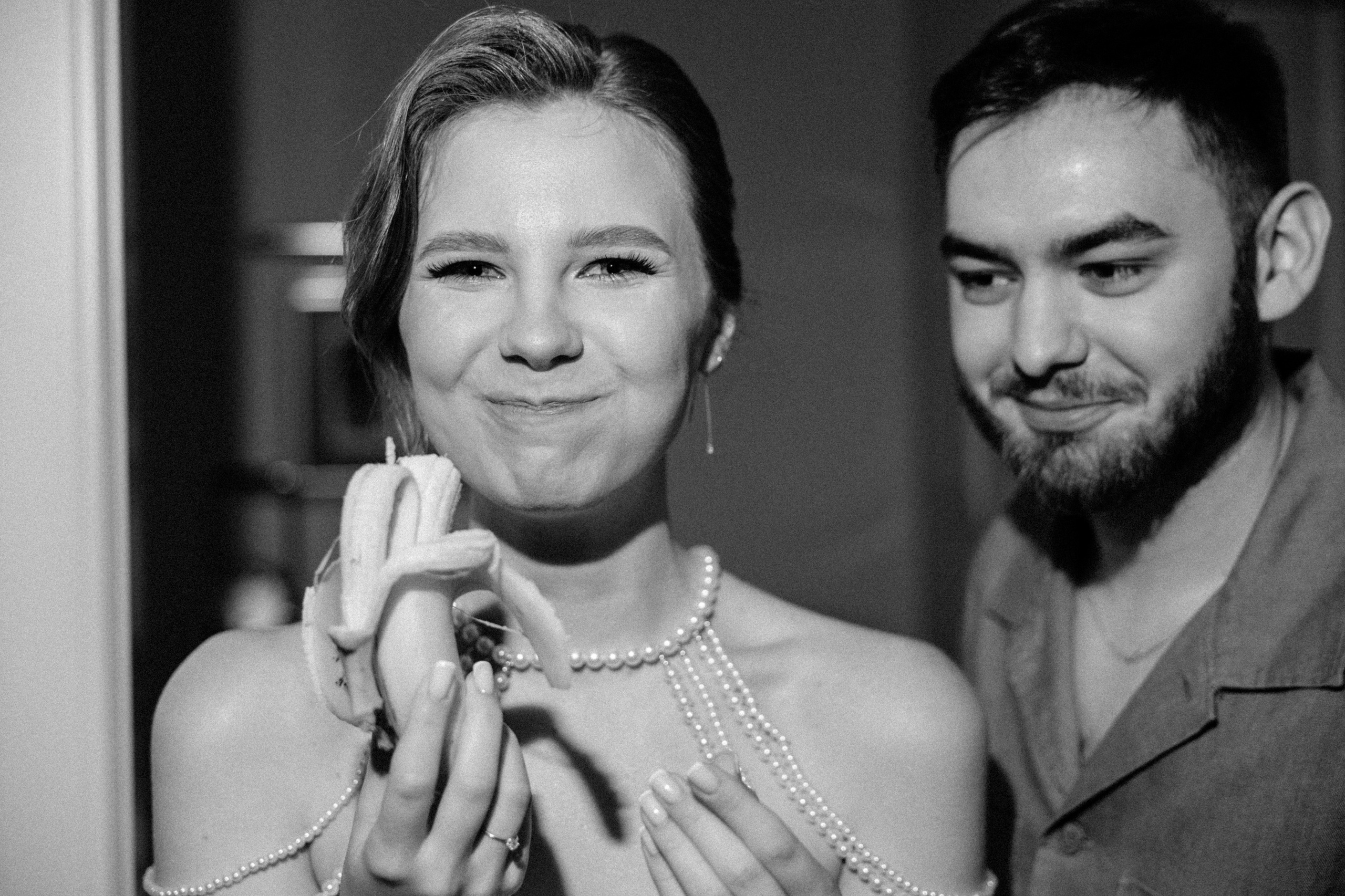 Черно-белое фото жениха и невесты, улыбающихся, невеста ест банан.