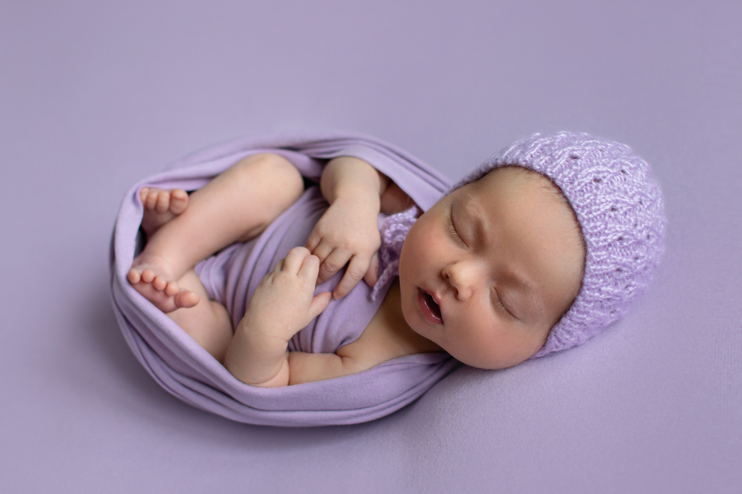 новорожденная девочка на сиреневом фоне