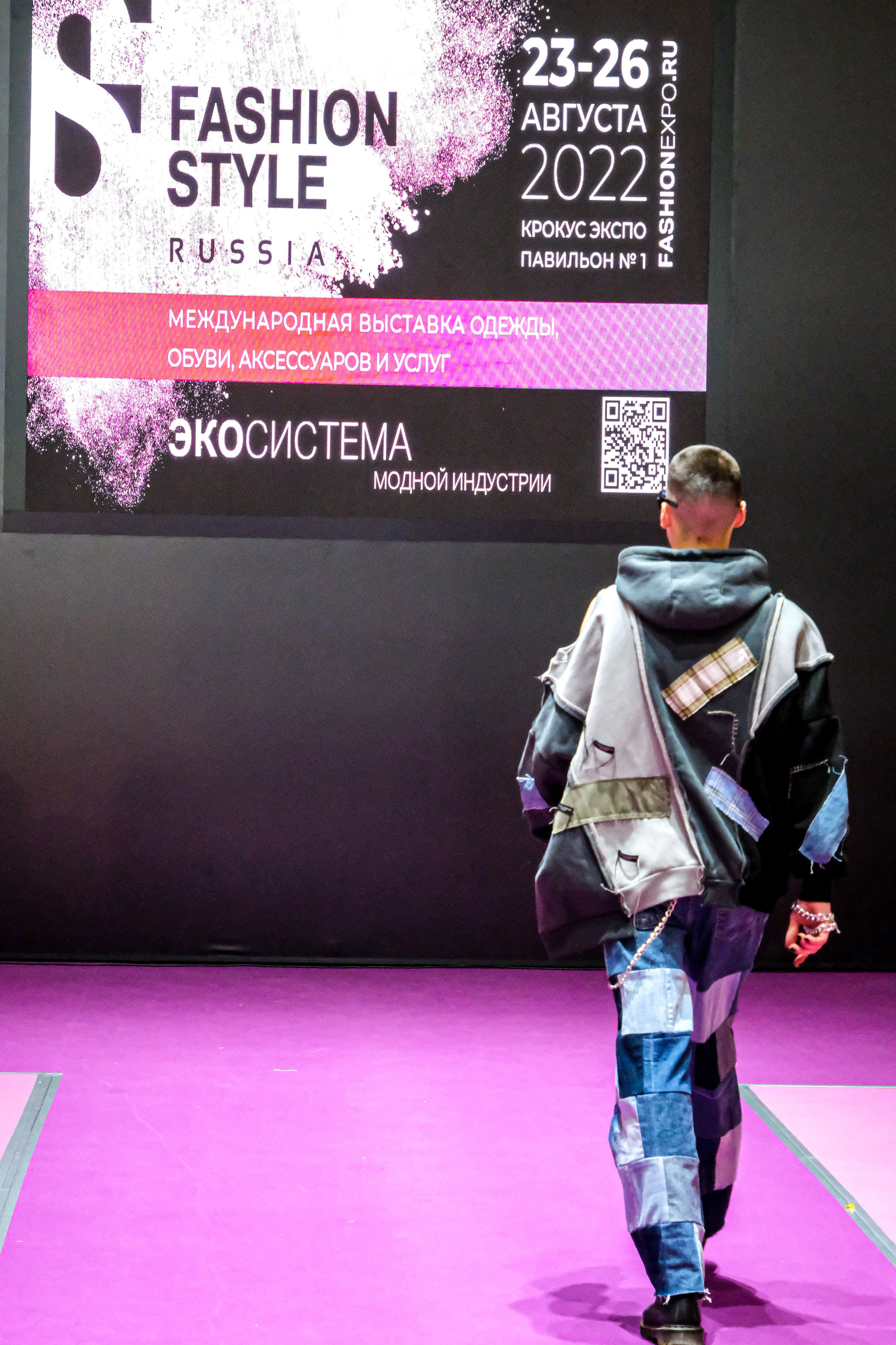  "Модели в ярких нарядах проходят по подиуму во время показа мод, освещенные яркими софитами и окруженные восторженными зрителями."