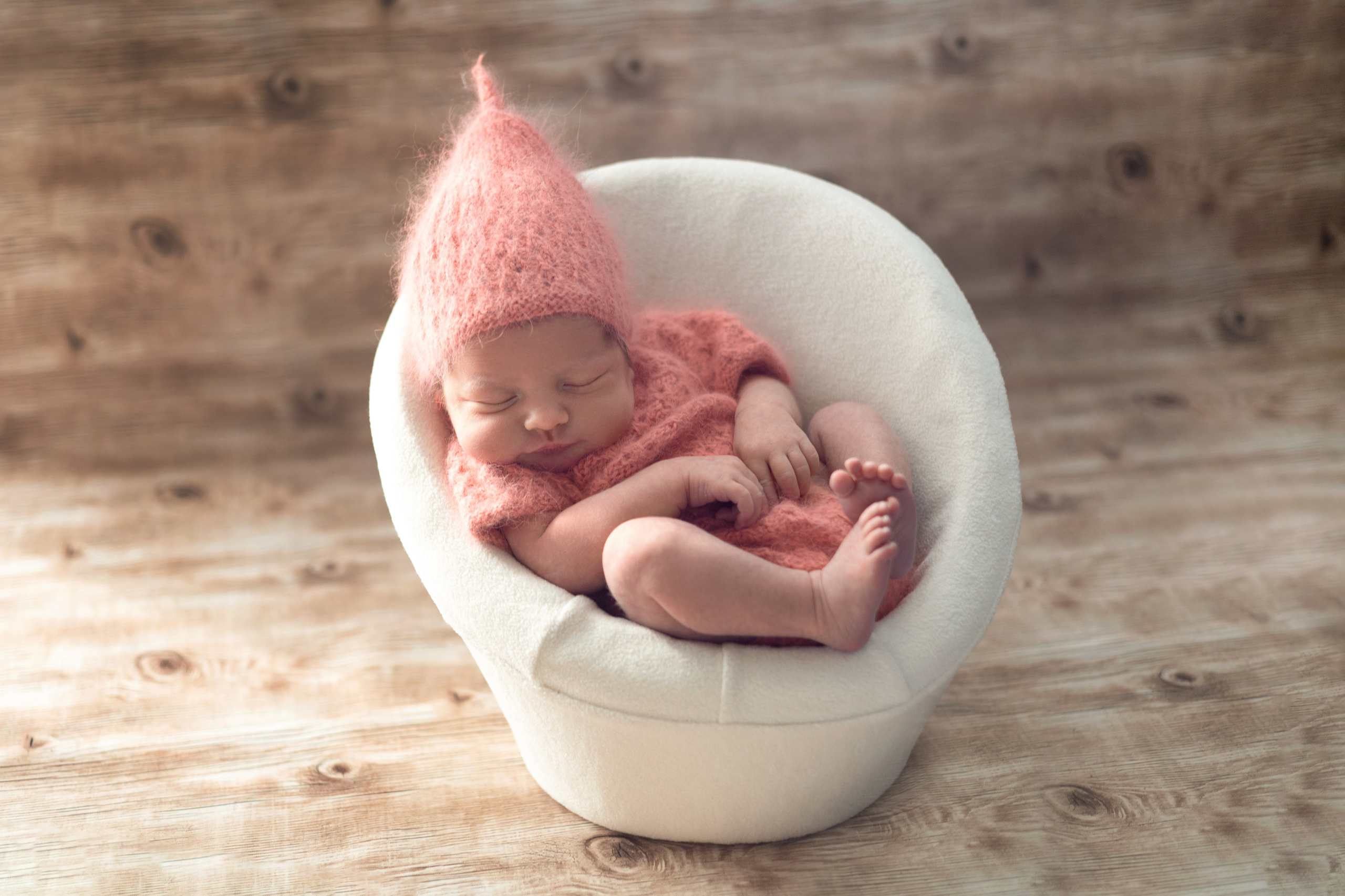 модный персиковый цвет на новорожденной малышке в кресле на фоне сандалового дерева