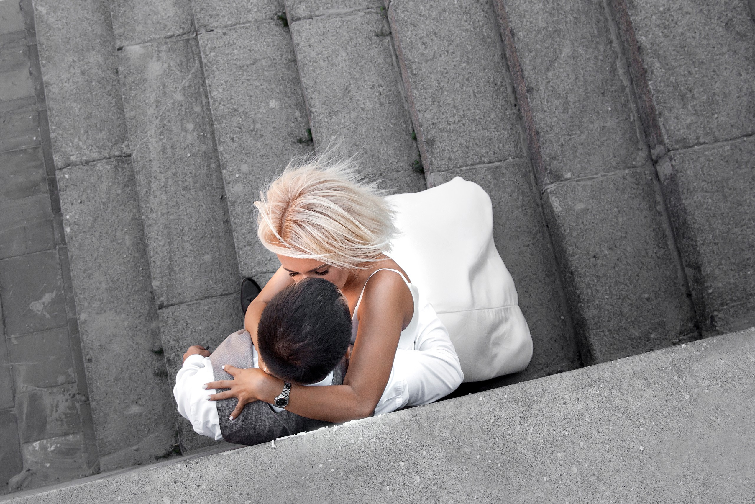 Невеста обнимает жениха у стены на лестнице в городе, вид сверху