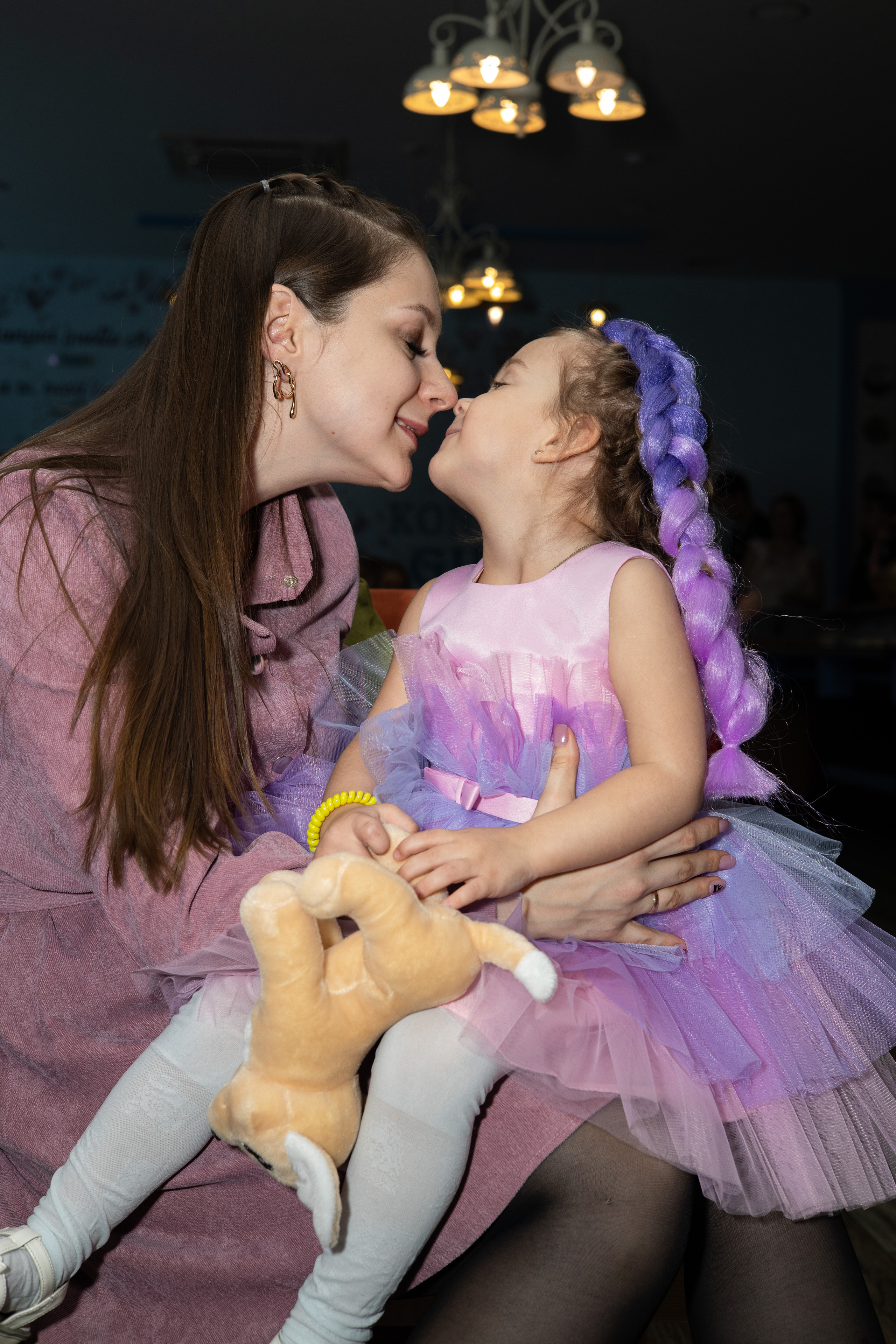 Маленькая девочка сидит у мамы на коленях, целует маму. Детский день рождения  Астрахань.