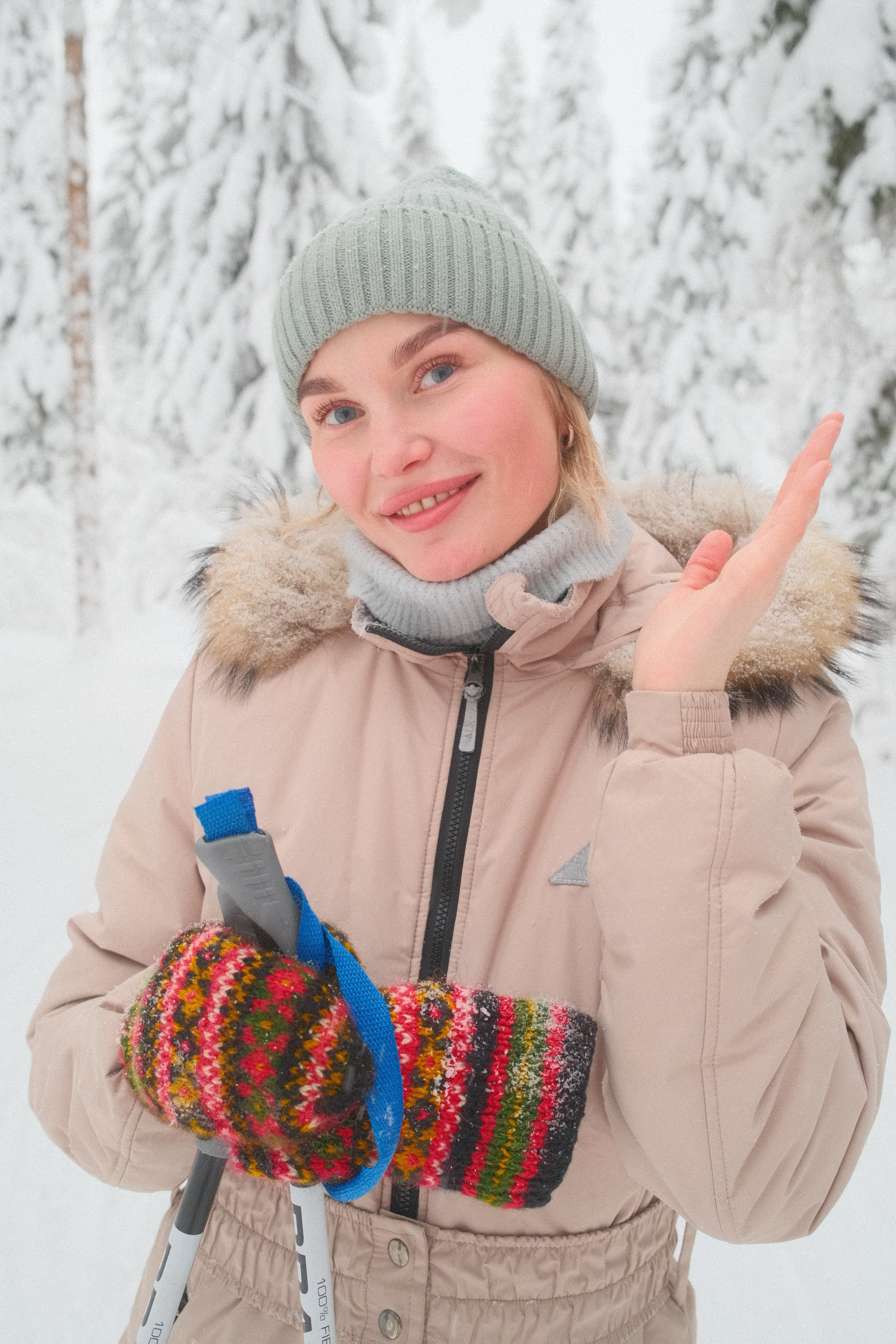 Девушка в бежевом лыжном костюме на лыжах в заснеженном зимнем лесу