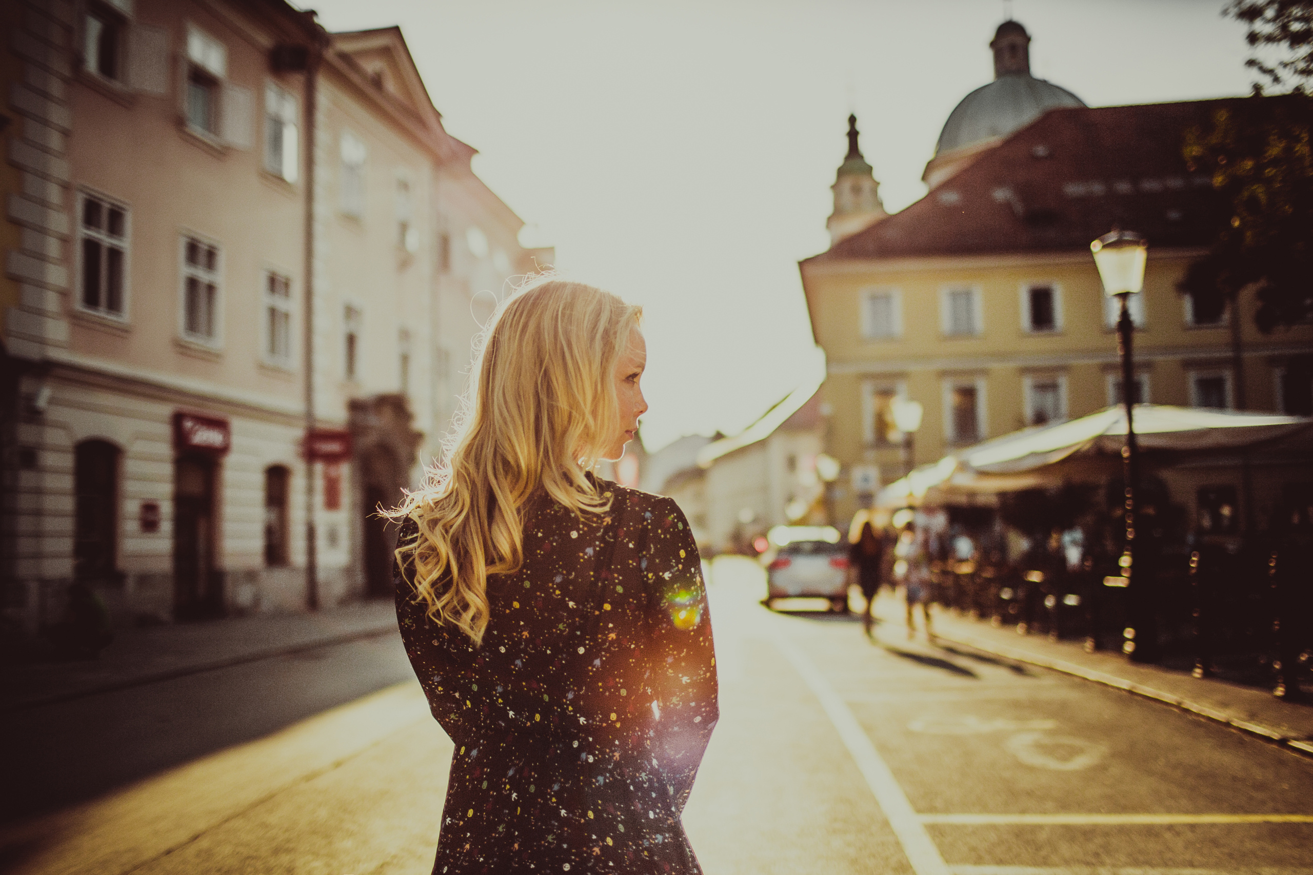 блондинка в темном платье в контровом свете на улице города