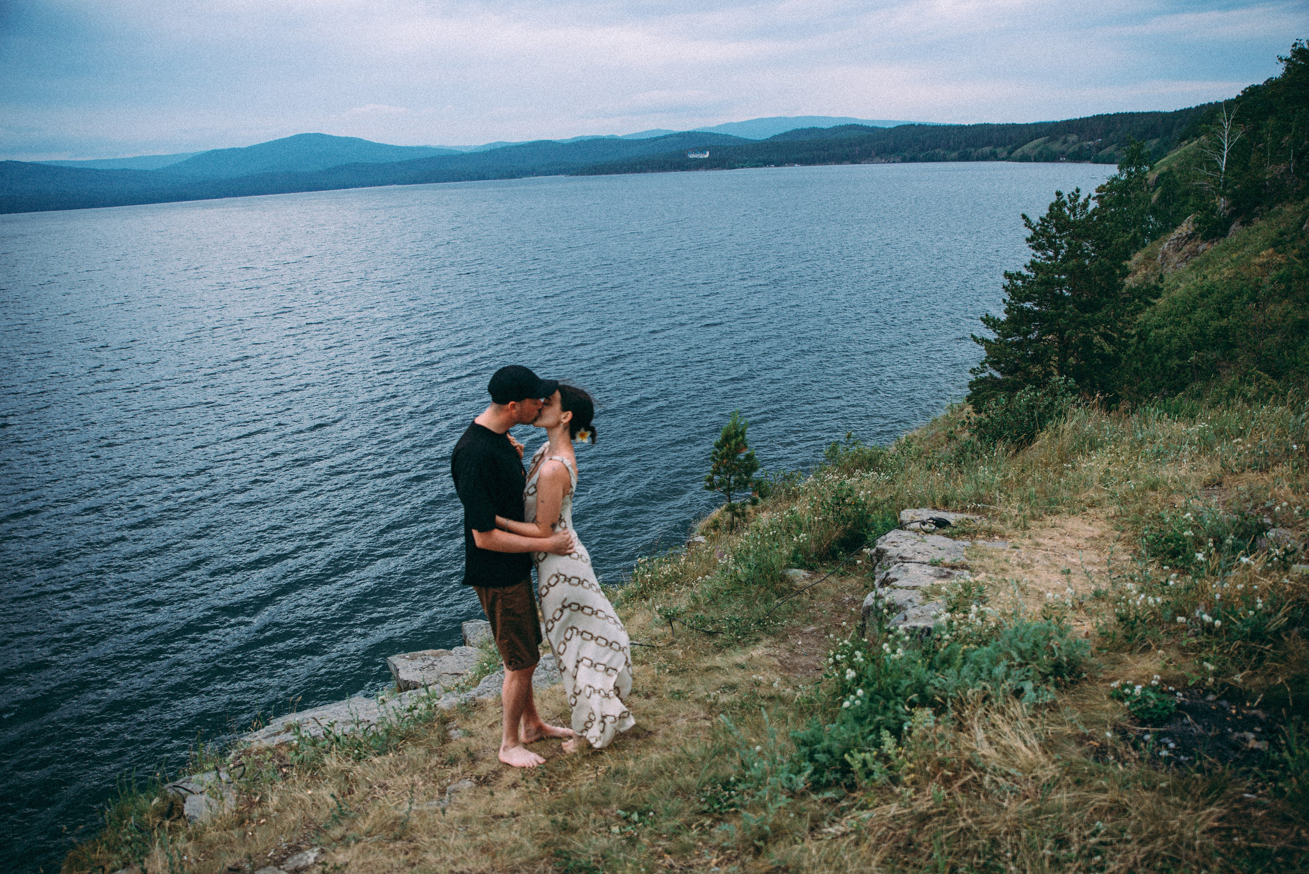 пара влюбленных целуется на берегу у обрыва