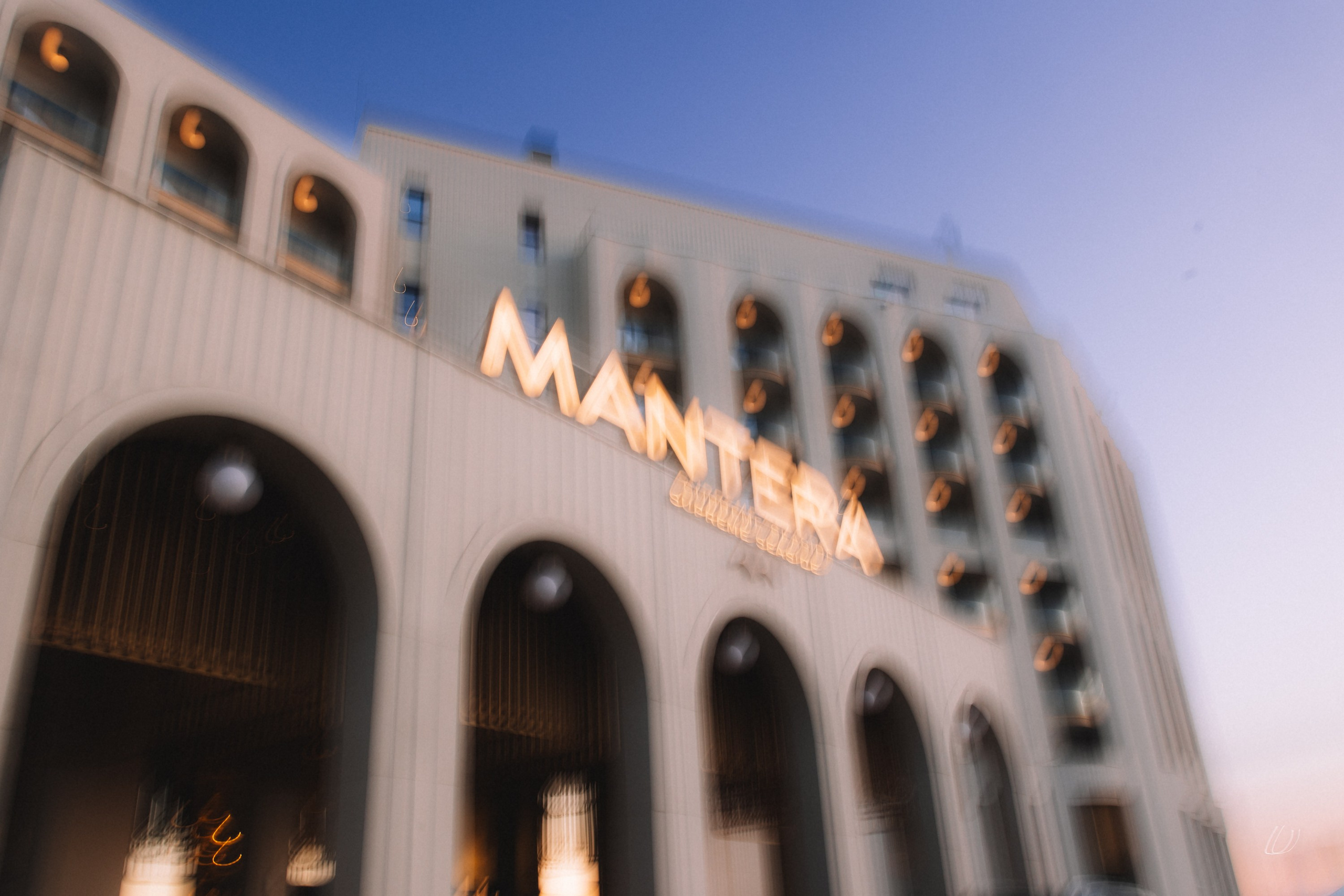 Архитектура: Вечерний вид на фасад отеля Mantera Supreme Seaside с подсвеченной вывеской на фоне сумеречного неба.