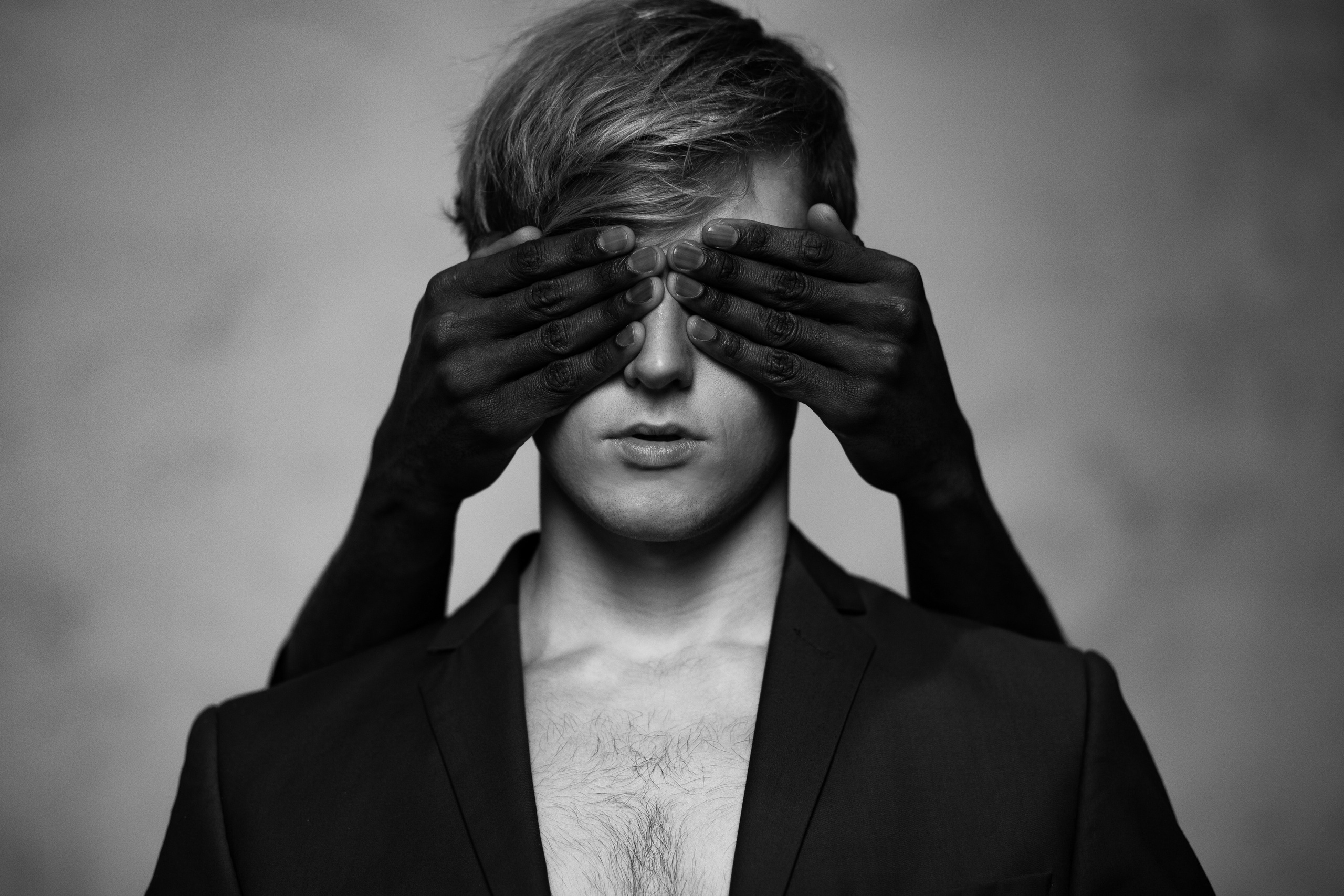 Черные руки закрывают глаза белому парню