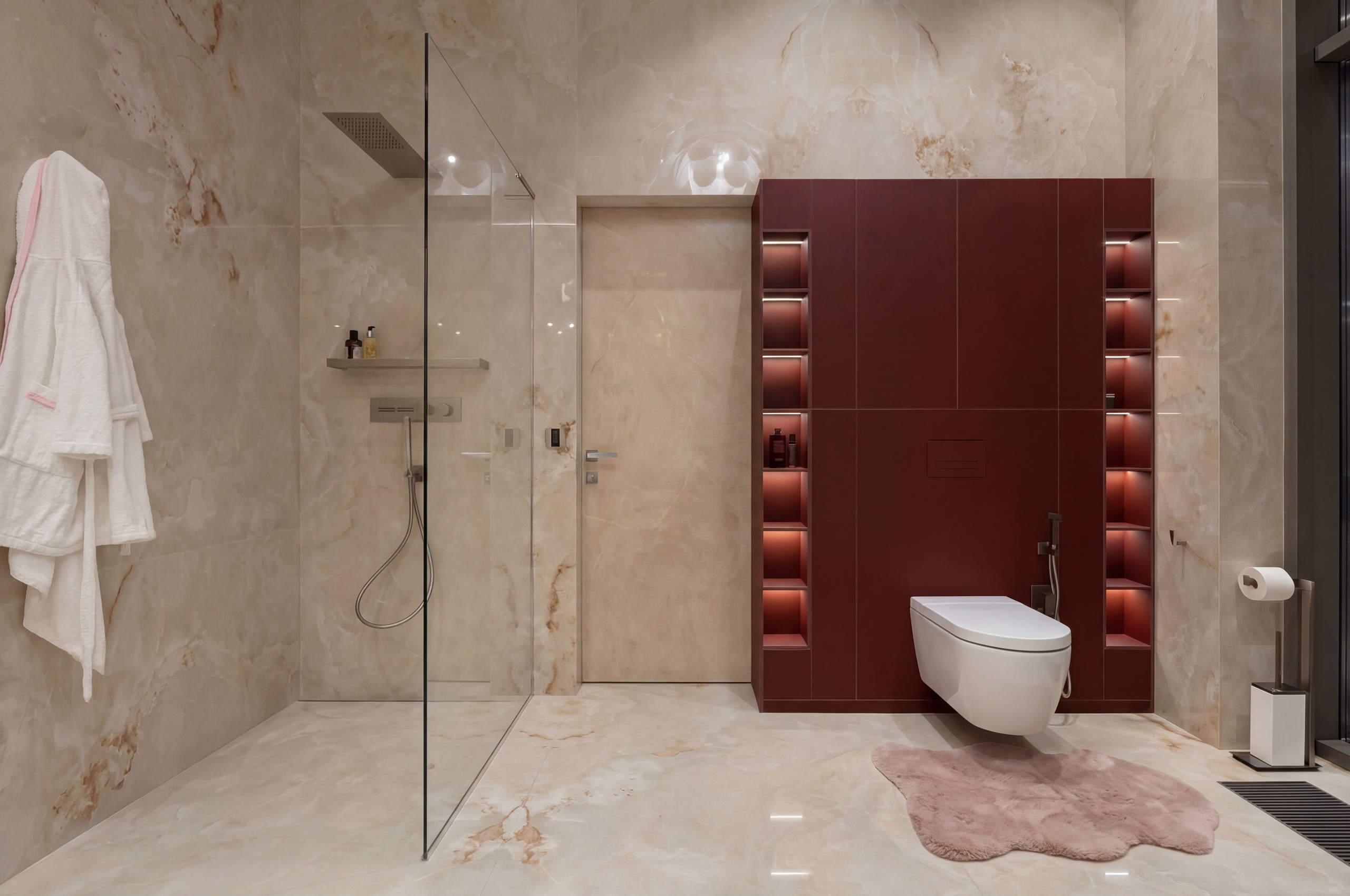 Минималистичный дизайн санузла от Валерии Котович: стены из глянцевого оникса, встроенный шкаф винного цвета с подсветкой ниш, подвесной унитаз и стеклянная душевая перегородка.