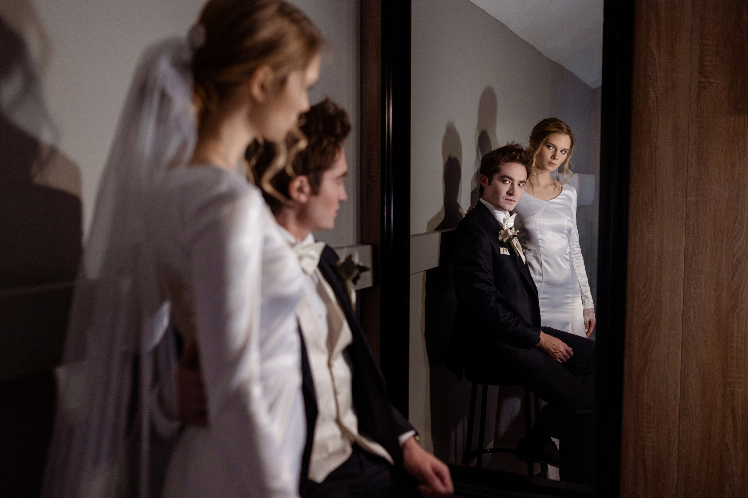 Жених и невеста смотрят на себя и на падающие тени в зеркале.