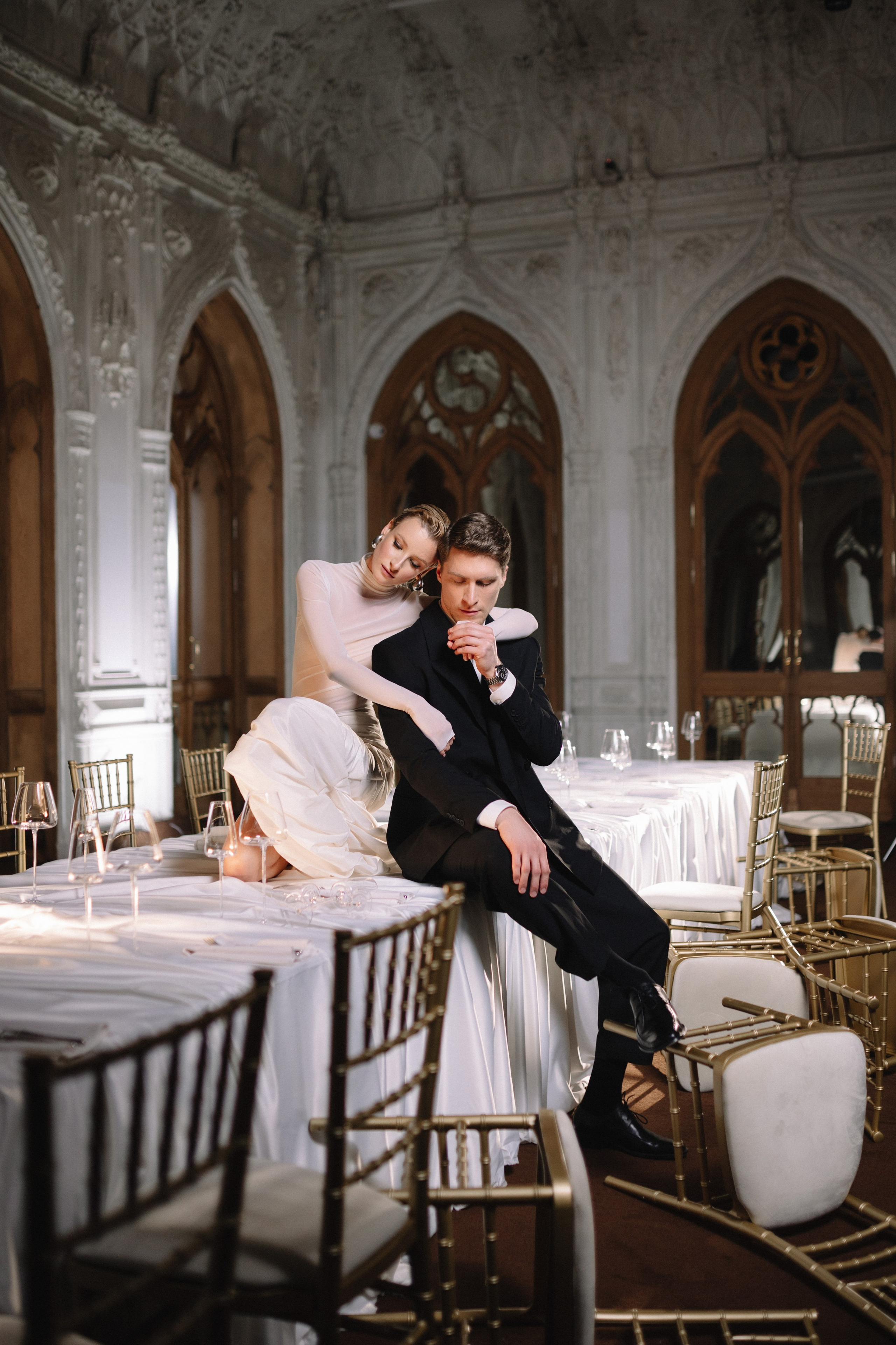 Восторженные взгляды зрителей направлены на пару, появившуюся в центральном проходе, наполняя сцену радостью и гармонией.