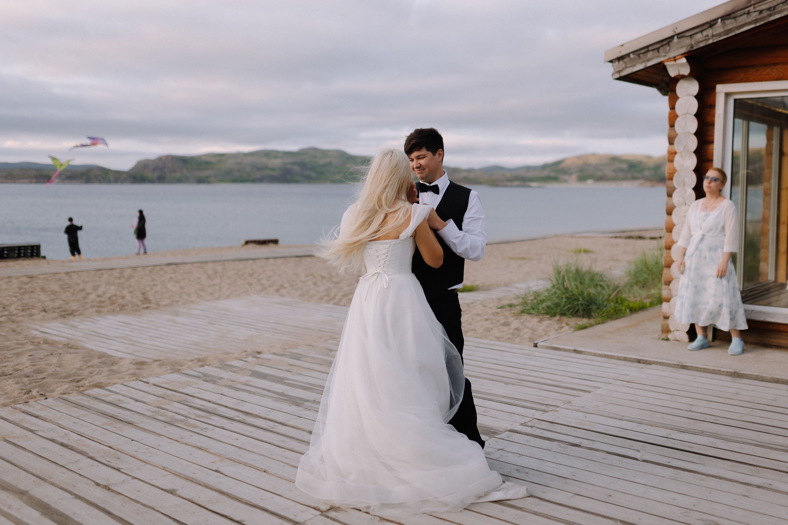 Закат солнца над Баренцевым морем и молодожёны, идущие рука об руку вдоль берега.