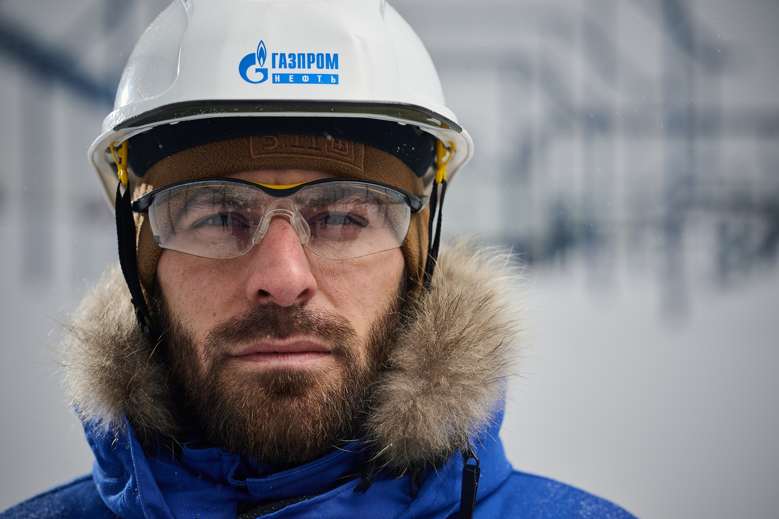 крупный портрет сотрудника нефтегазовой промышленности в зимнее время на фоне куста добычи нефти