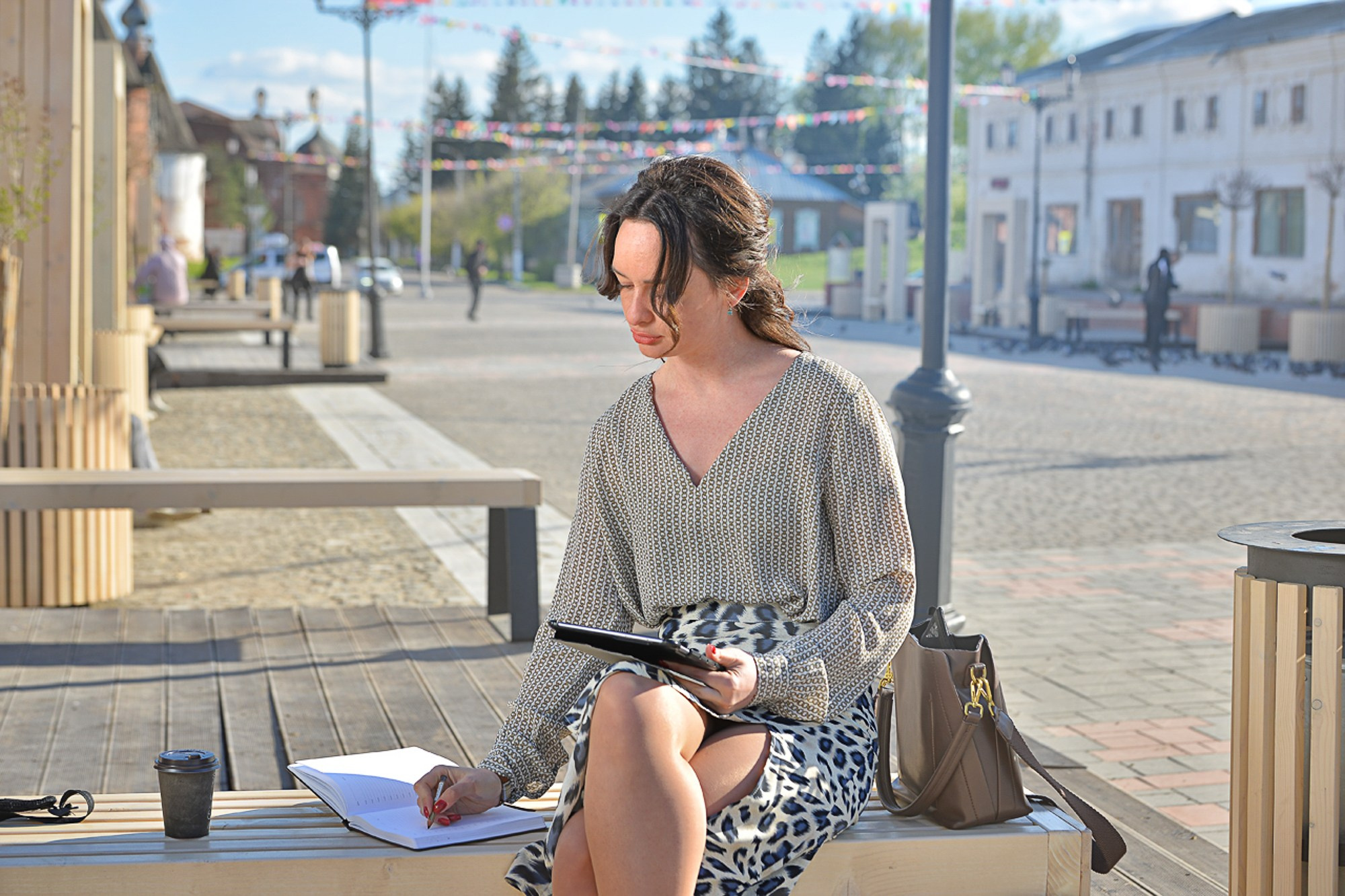 Фотограф в Юрьев Польском и области симпатичная девушка сидит на скамейке в центре города с планшетом на коленях