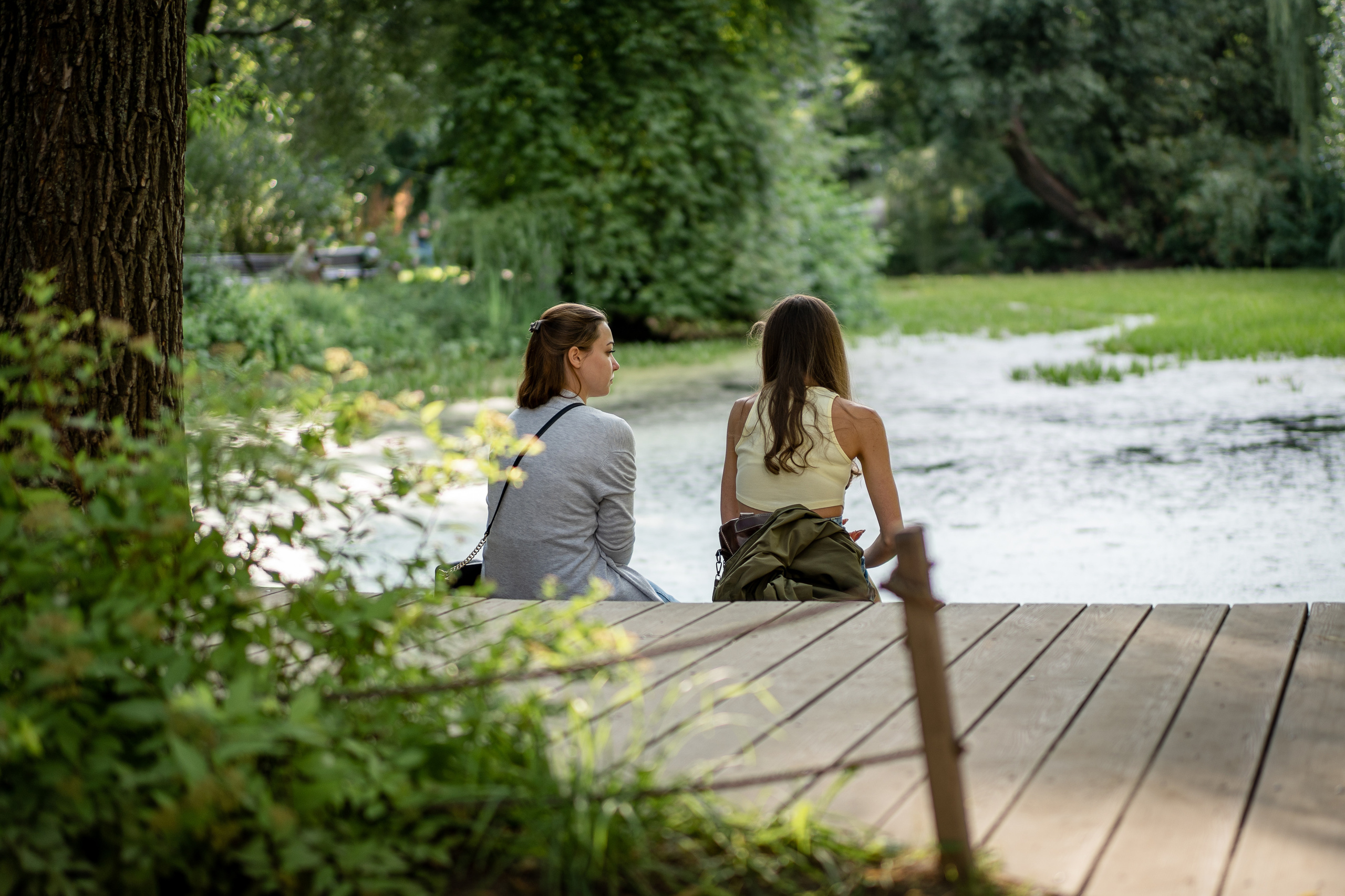 Две девушки сидят у пруда в Аптекарском огороде в Москве