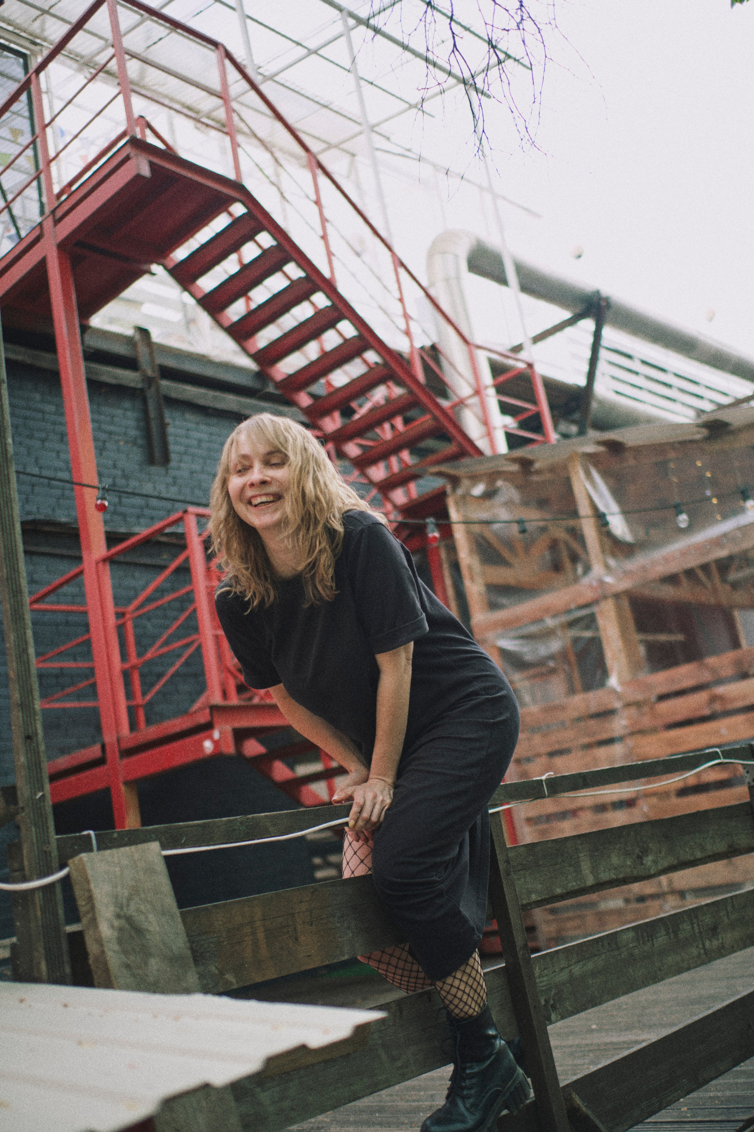 Женщина перелезает забор, смеется