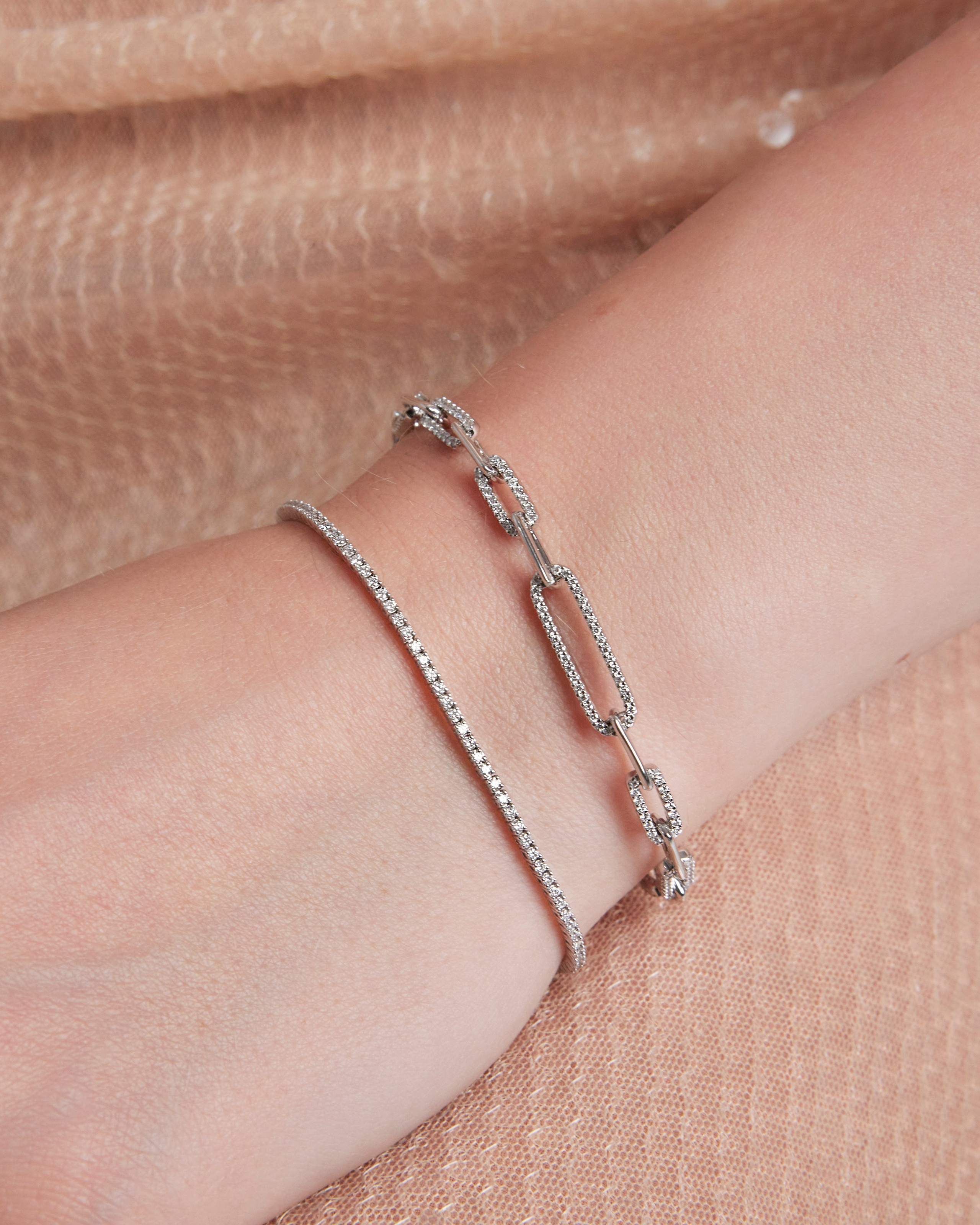 Minimalist gold bracelet on a model's wrist, complementing a soft beige background.