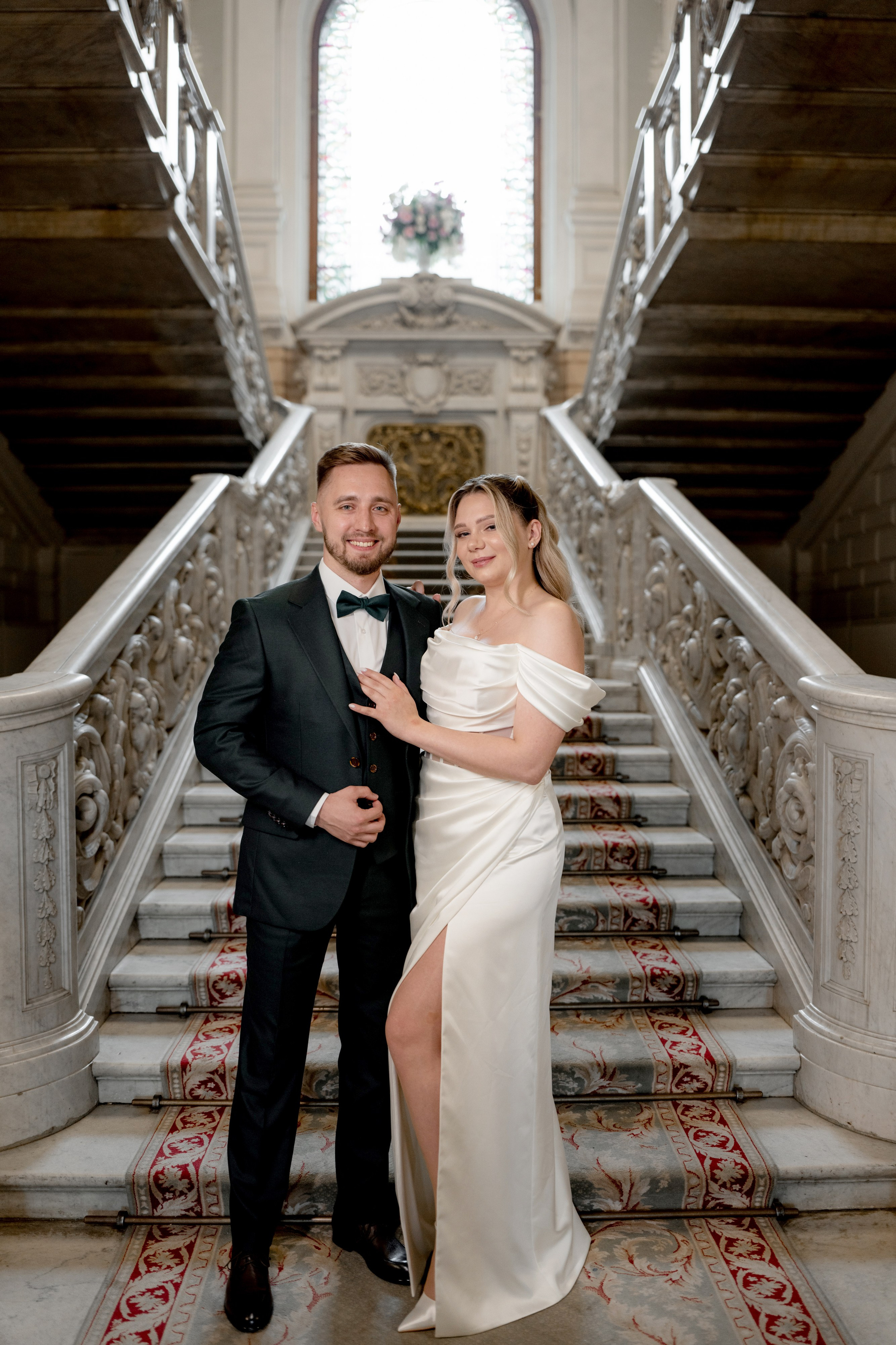 Свадебная фотосессия во Дворце Бракосочетания №1 Жених и невеста стоят у лестницы и позируют фотографу.