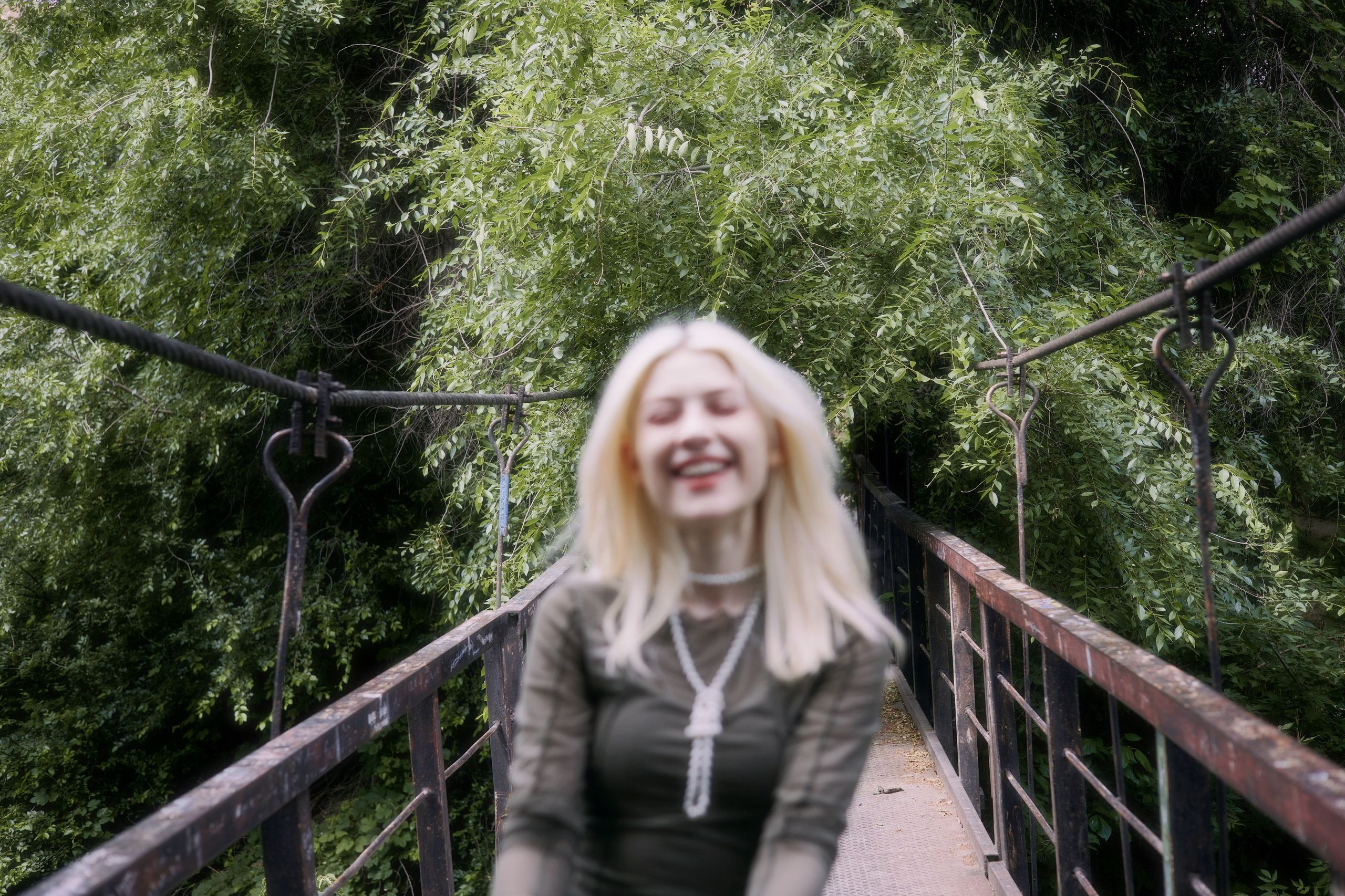 Искренний кадр с улыбающейся девушкой на мосту в зелени