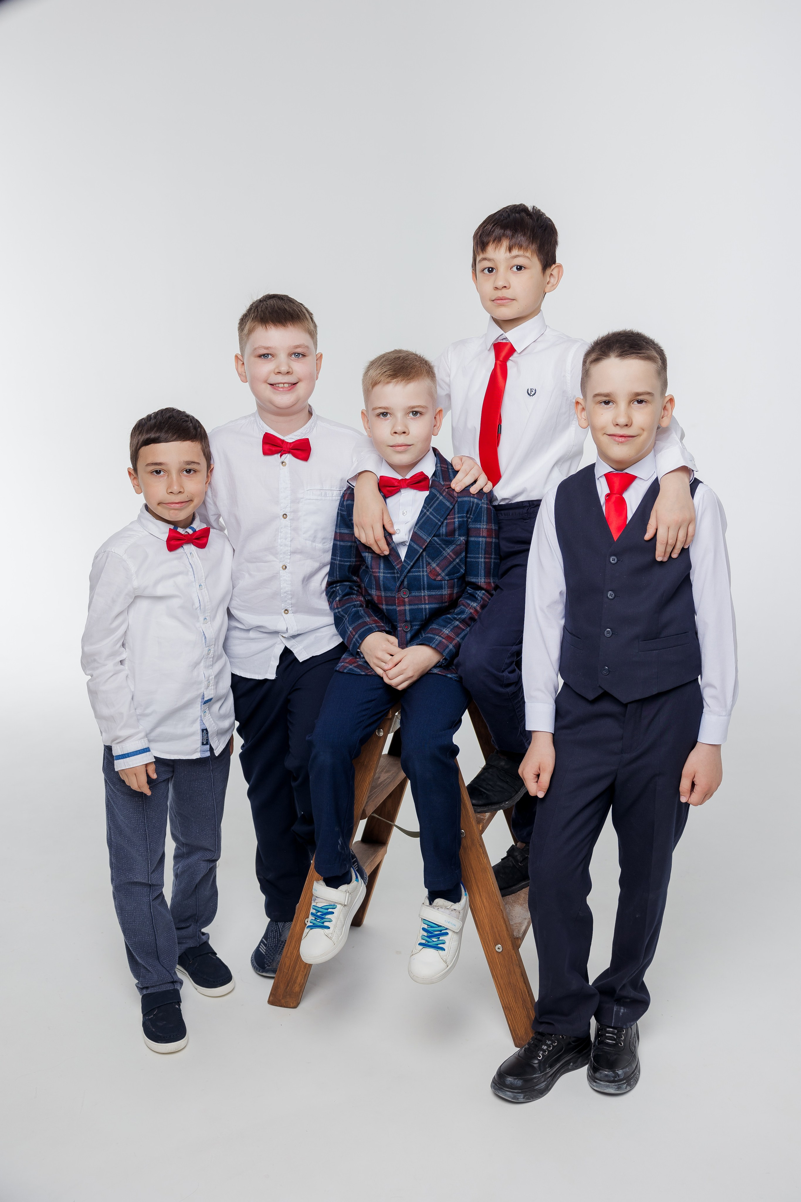 Группа мальчиков стоит вместе в студии в одежде с красными акцентами