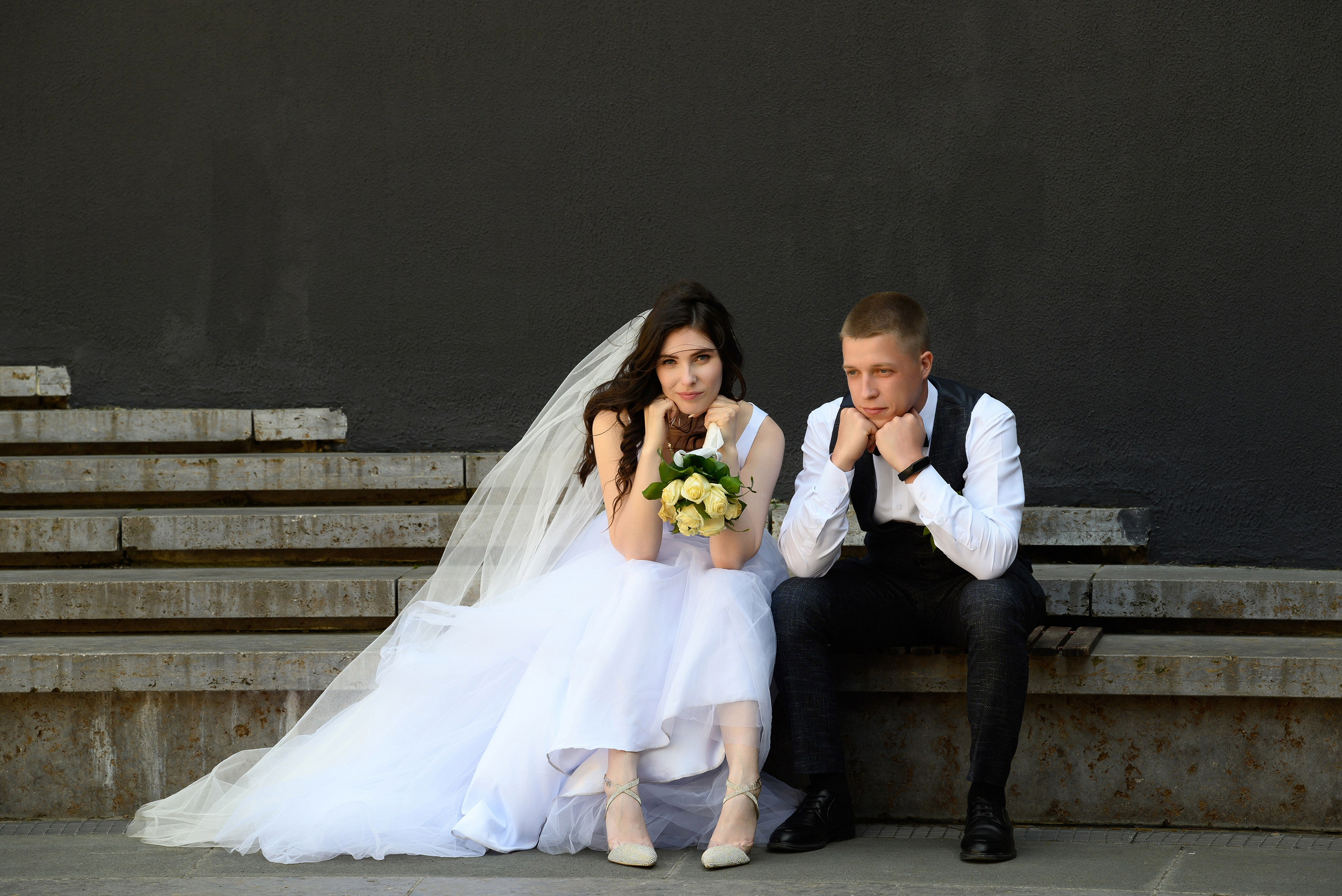 Жених и невеста сидят на ступенях.