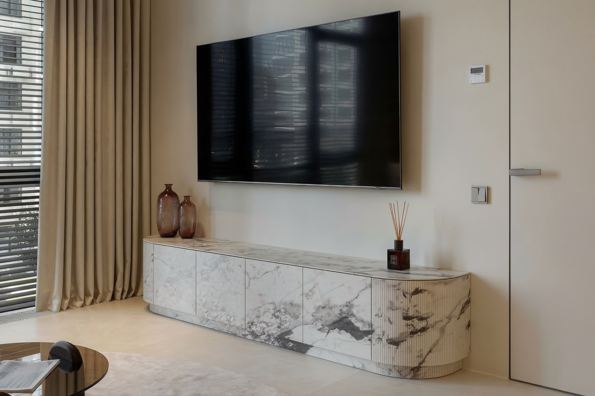 Подвесная ТВ-тумба из белого мрамора с радиусным рифленым фасадом в ЖК ONYX Deluxe. Интерьер гостиной от Валерии Котович.