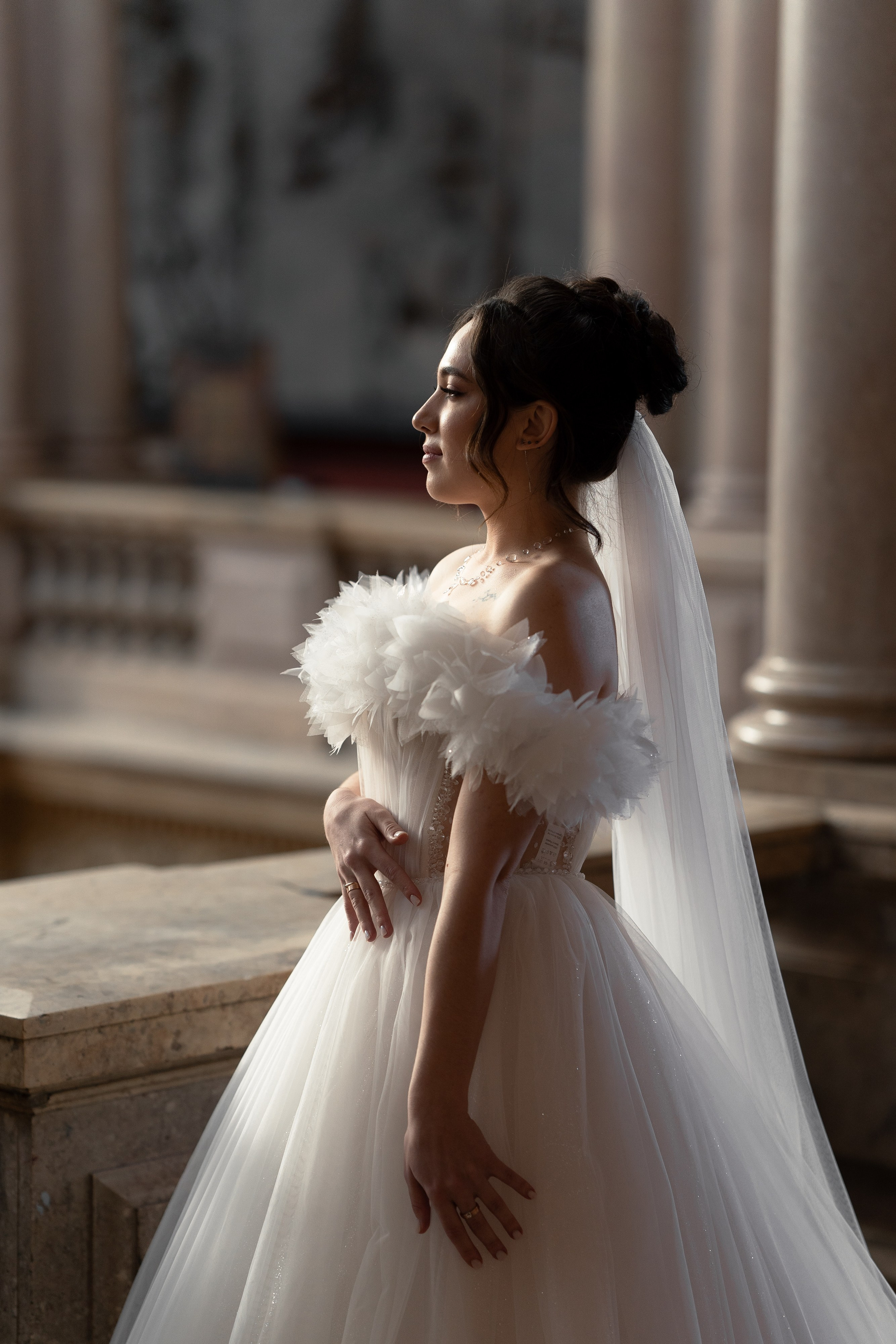 Невеста в пышном платье стоит в лучах солнца в академии Штиглица