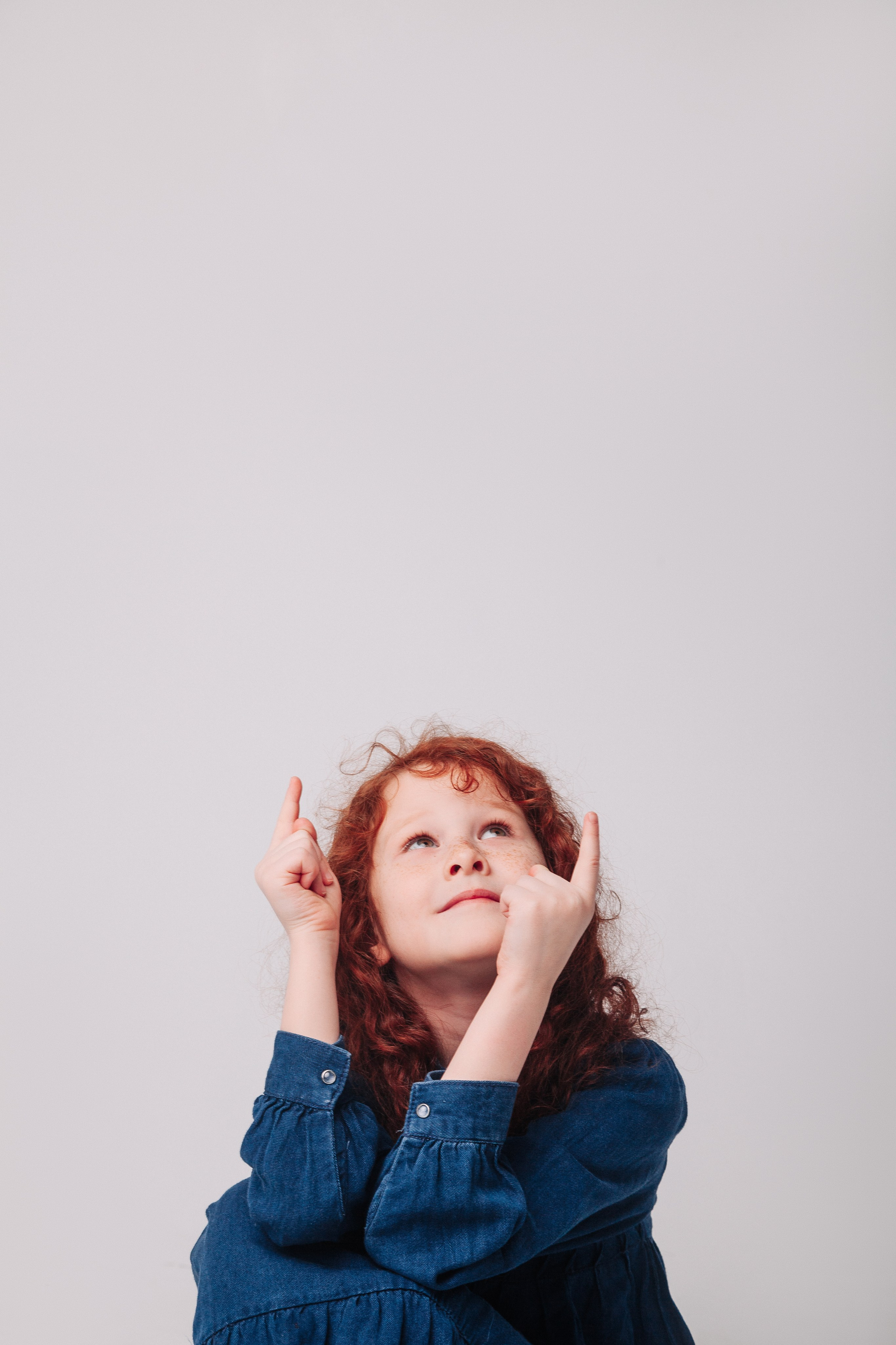 Рыжая кудрявая девочка показывает наверх