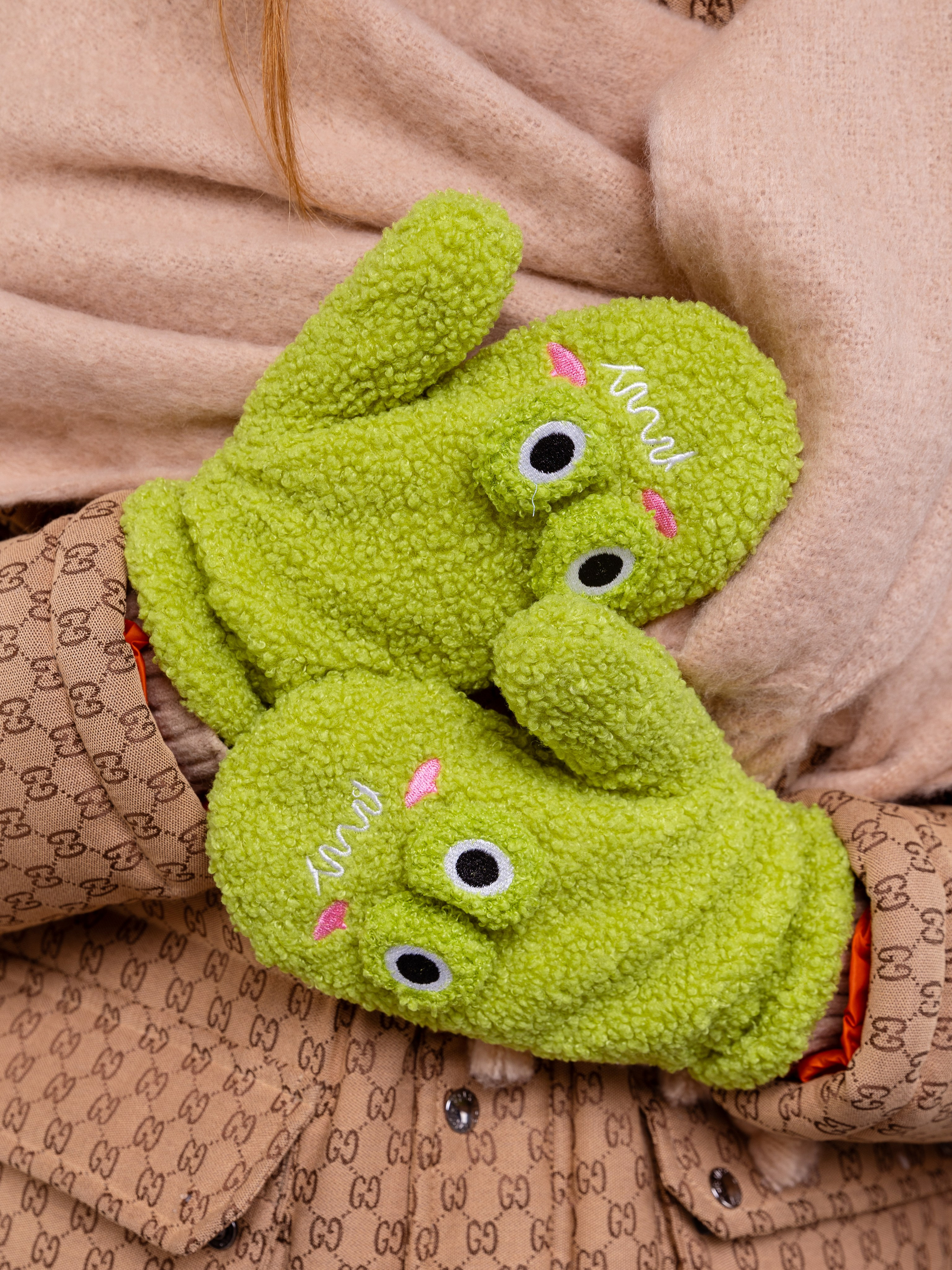 Девушка прижала к груди руки в зеленых рукавичках.