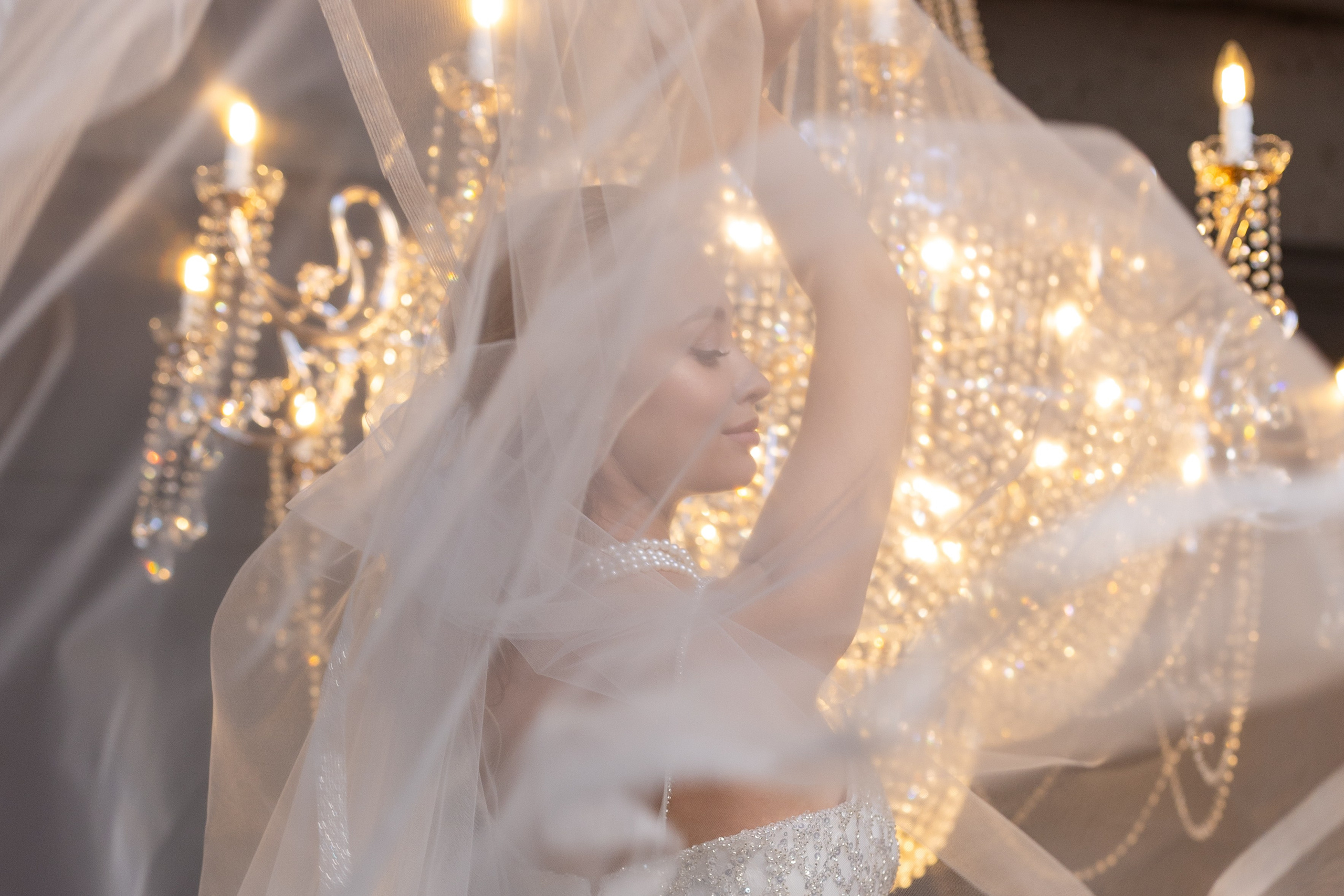 Невеста на фоне люстры, окутанная вуалью.