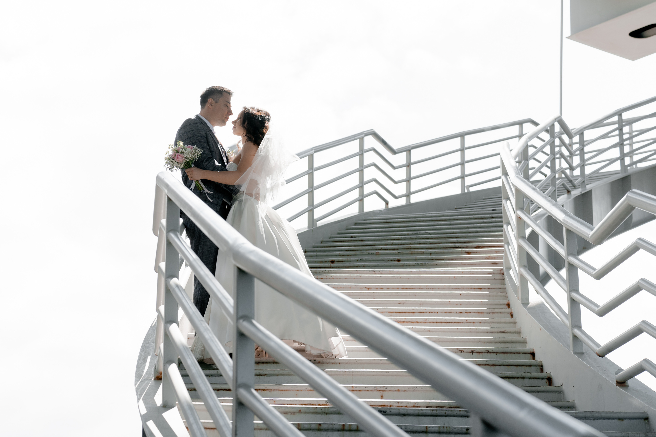 жених и невеста стоят на мосту как будто парят в воздухе