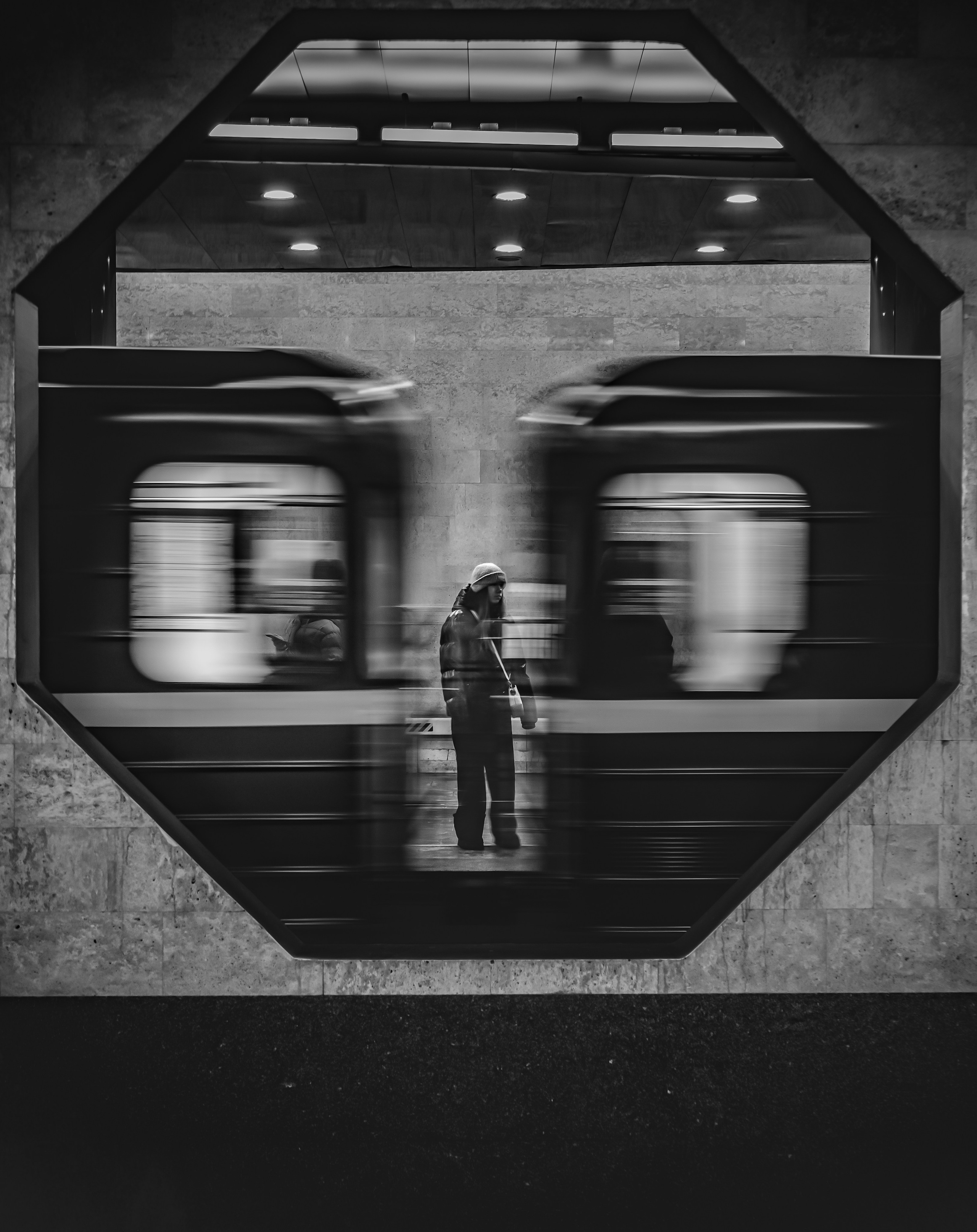  Метро СПБ. Чёрно-белая фотография девушки в шапке на фоне размытого поезда в петербургском метро, отражение в стекле, креативный urban кадр, Евгений Мальцев.