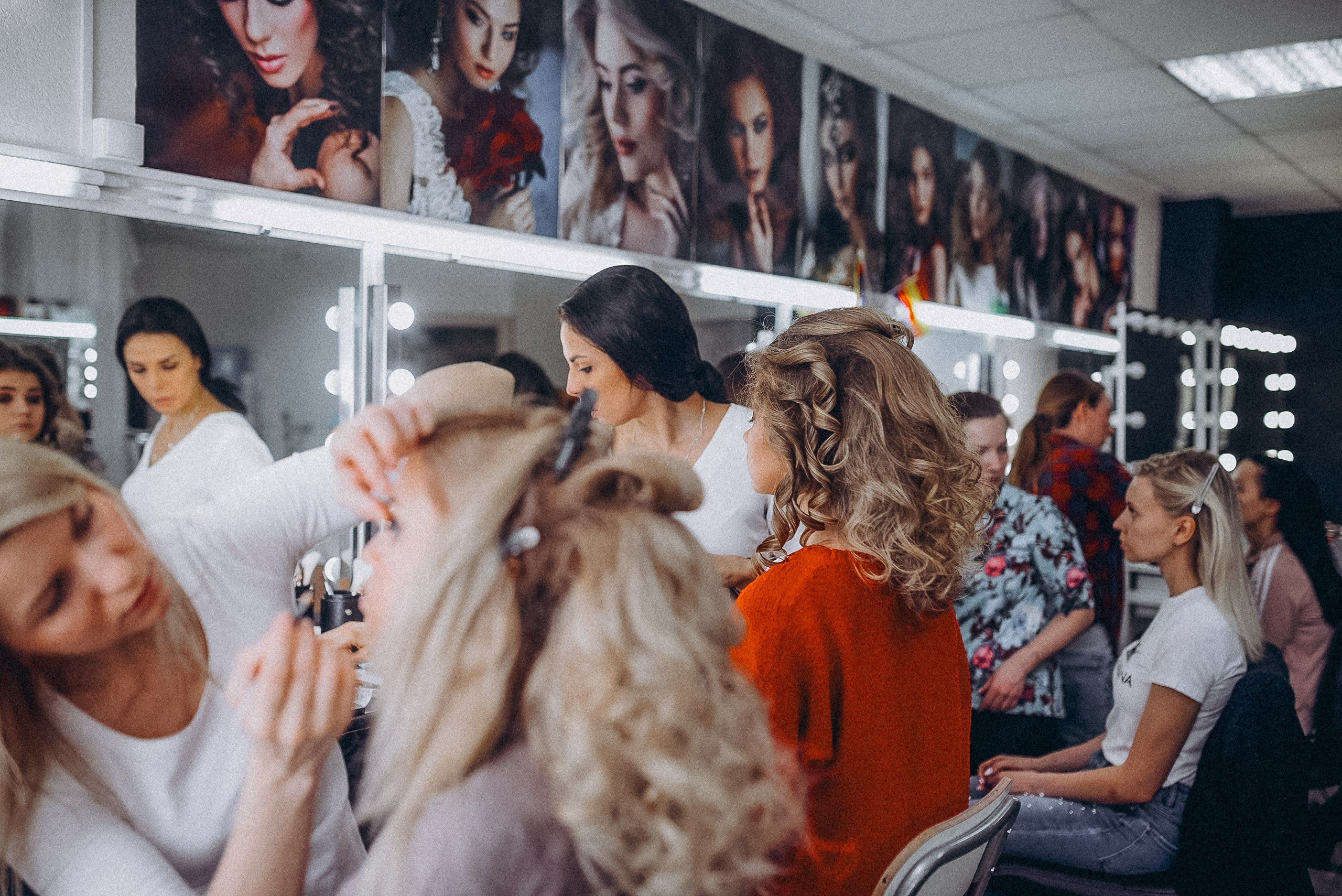 Динамичный кадр подготовки: суета, зеркала и профессиональное освещение в гримерке.