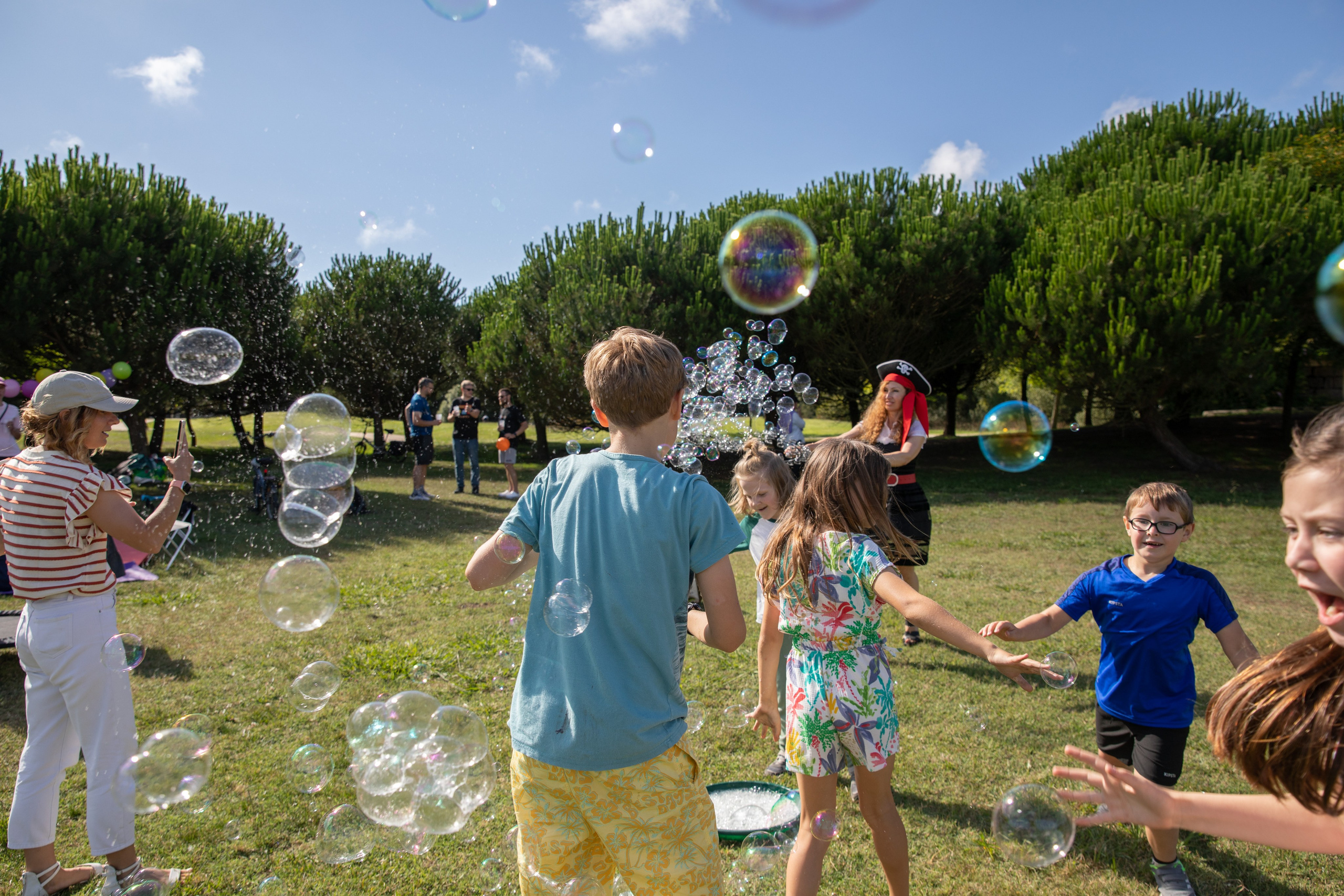 Park birthday photo shoot with kids having fun and soap bubbles in the air