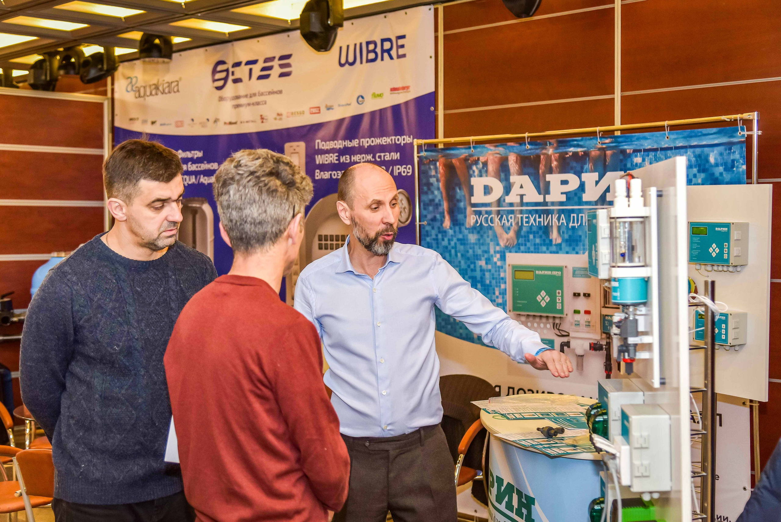 Репортажная съемка с выставки в Москве: снимок передаёт атмосферу общения между представителем компании и посетителями выставки.