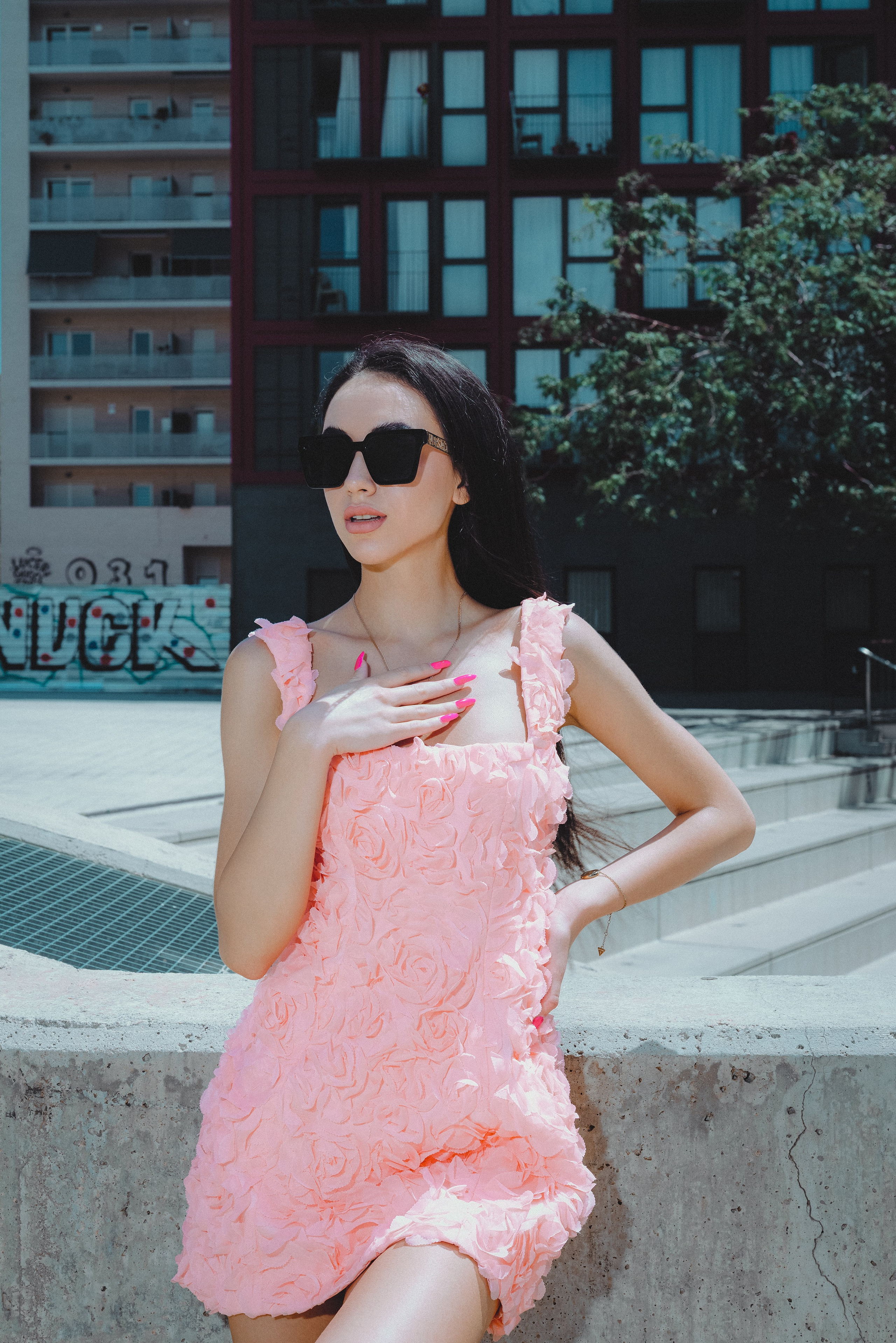 Romantic portrait of a girl in a pale pink outfit against Barcelona’s old stone walls.