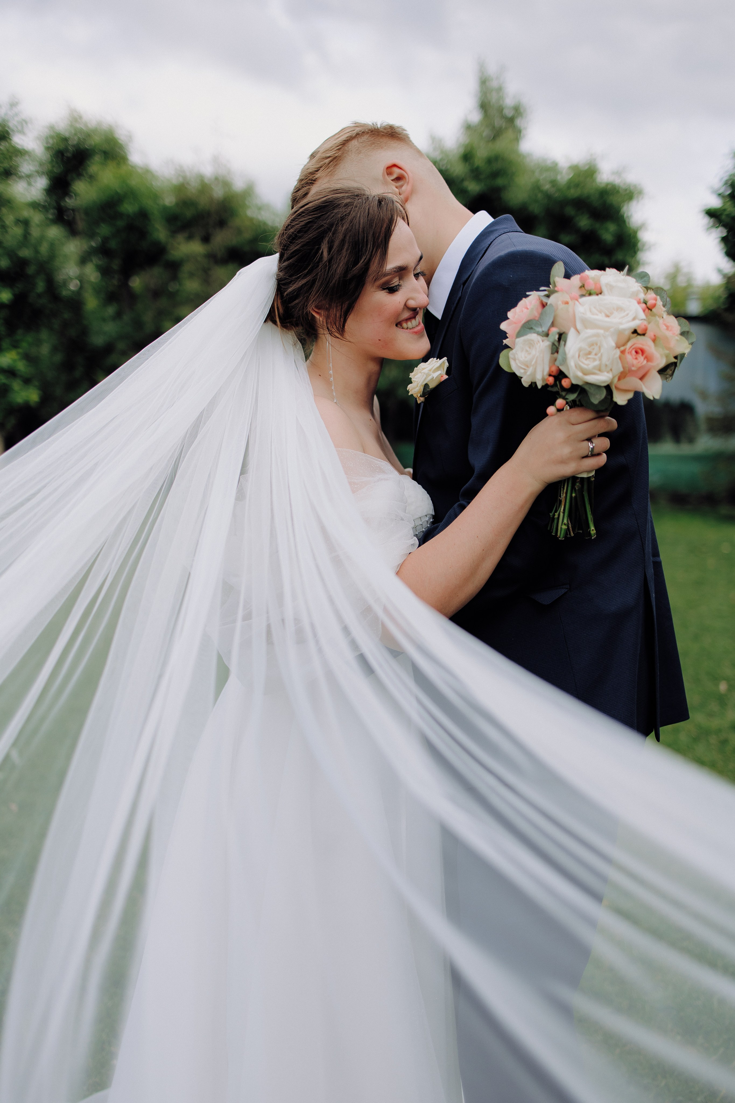 Невеста в белом платье с букетом цветов улыбается на свадебной церемонии