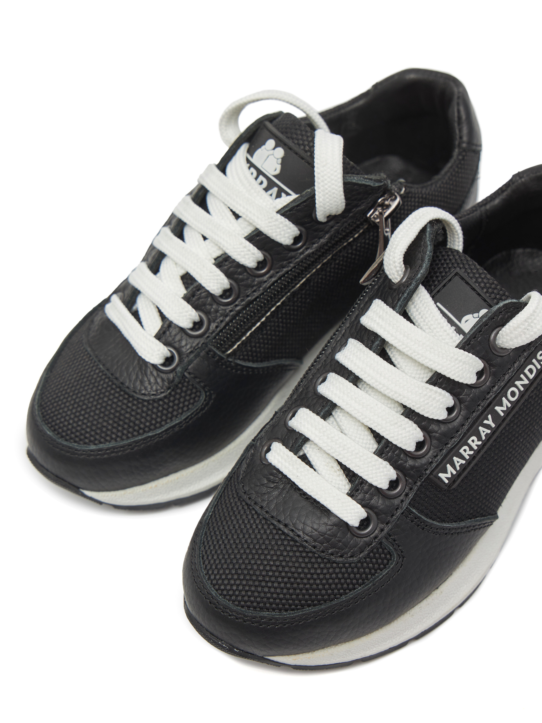 Кроссовки черного цвета с белыми шнурками на белом фоне близко